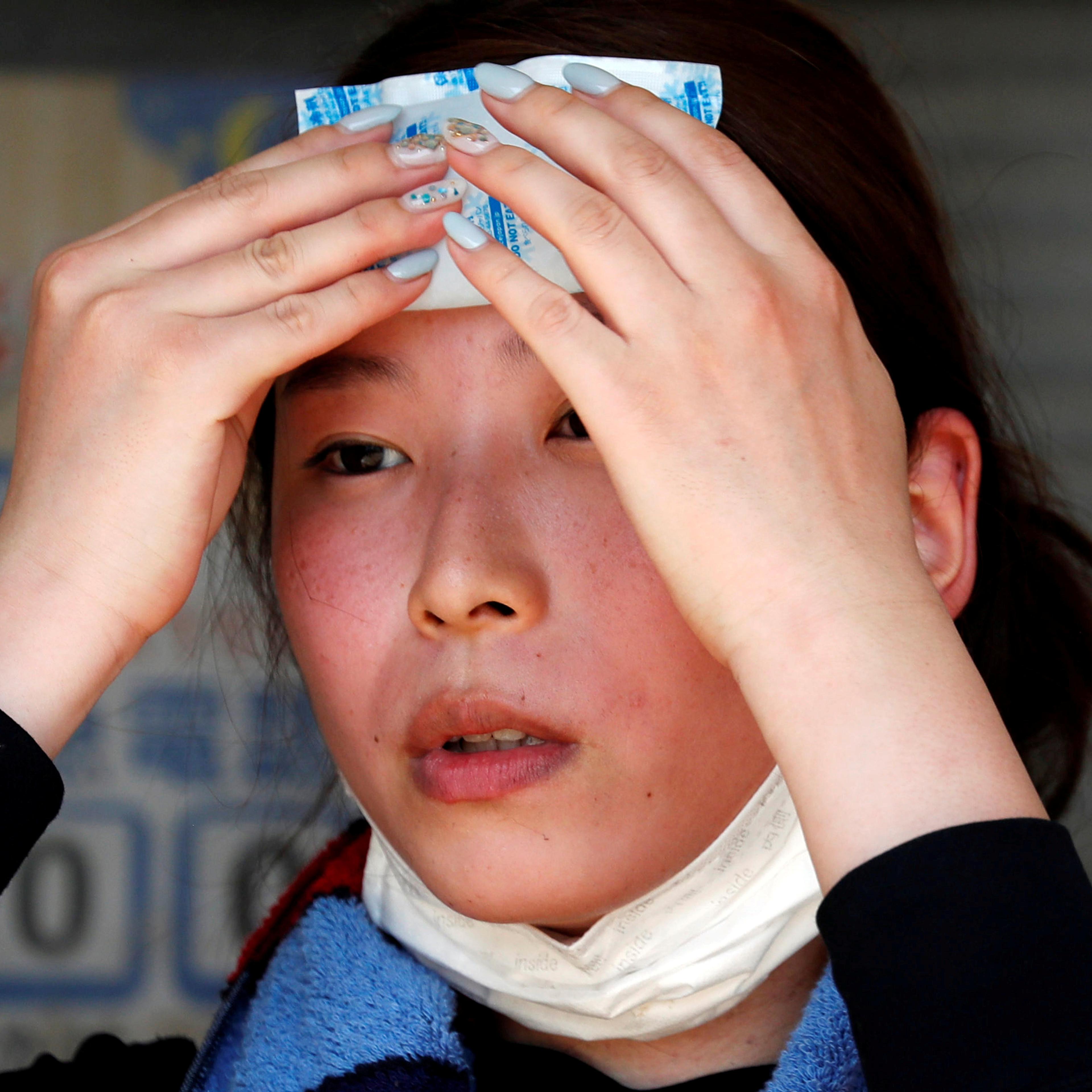 FILE PHOTO: A volunteer, for recovery work, uses a pack of refrigerant to a cool down as she takes a break in a heat wave at a flood affected area in Kurashiki