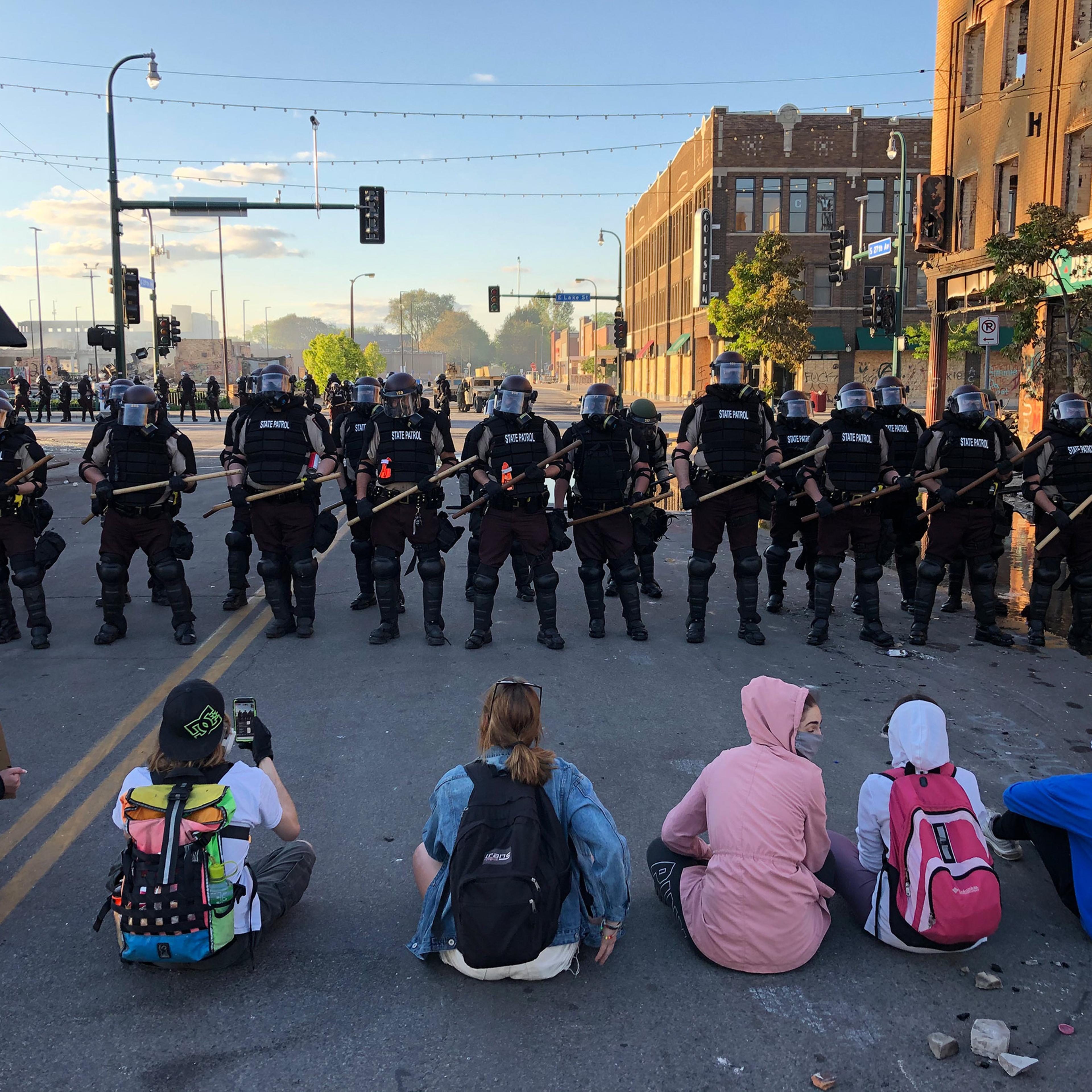 People sit on the street in front of a row of police officers during a rally in Minneapolis on May 29 after the death of George Floyd.