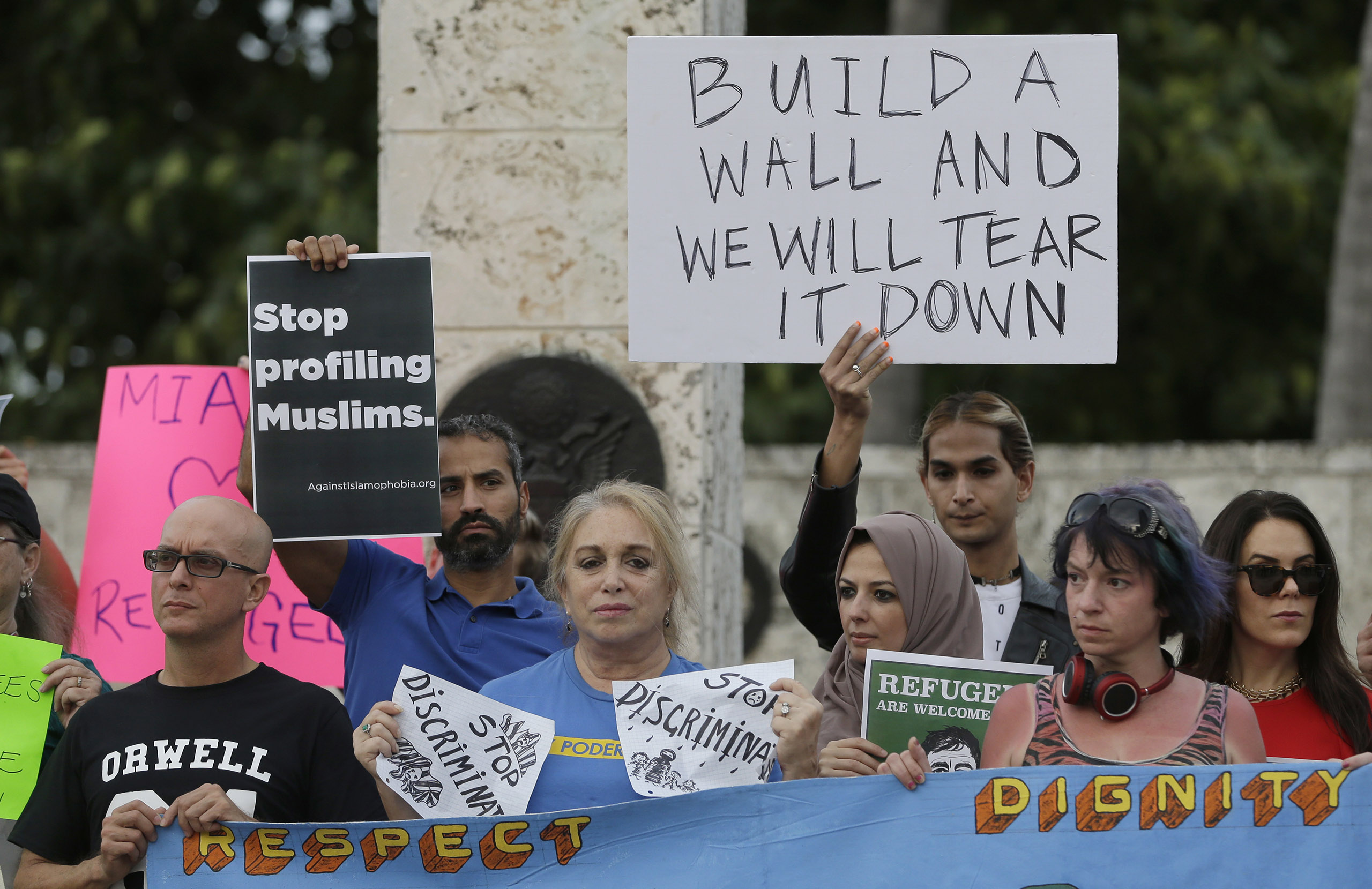 Protesters hold signs during a rally against President Donald Trump's executive order on immigration in downtown Miami. on Jan. 26, 2017.