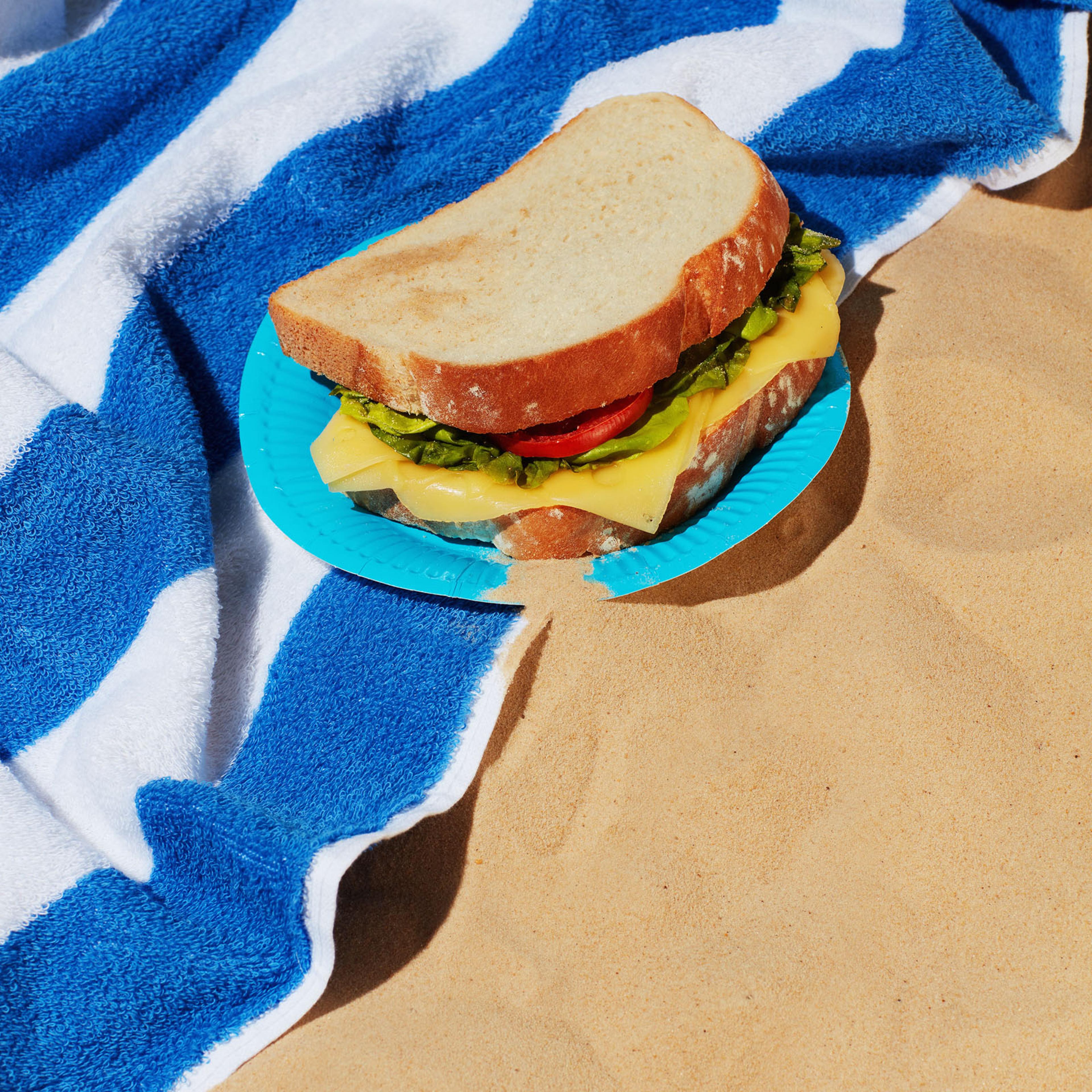 sandwich on blue and white beach towel