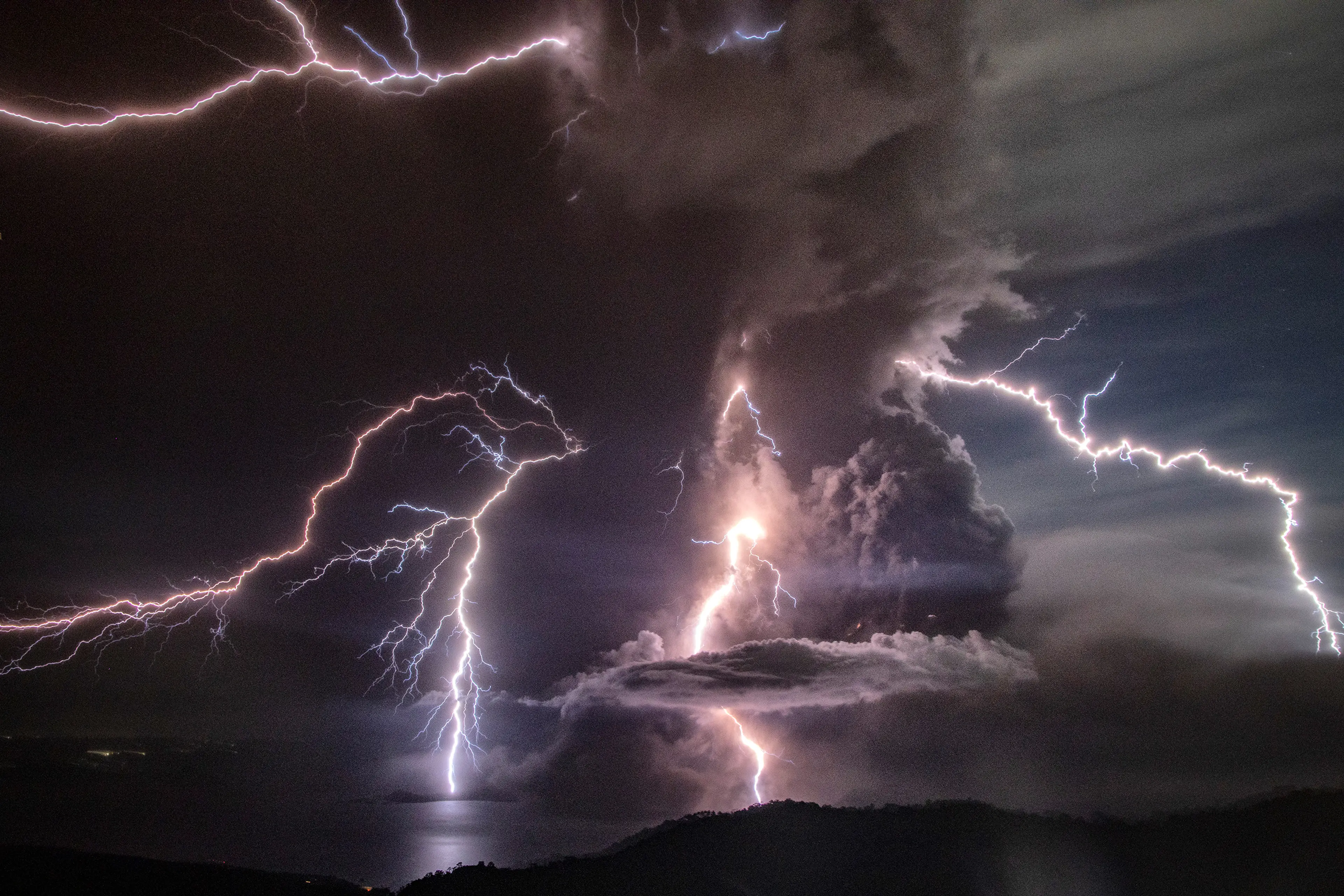 Lightning strikes as a column of ash surrounds the crater of the Taal volcano during an eruption, as seen from Tagaytay, on Jan. 12