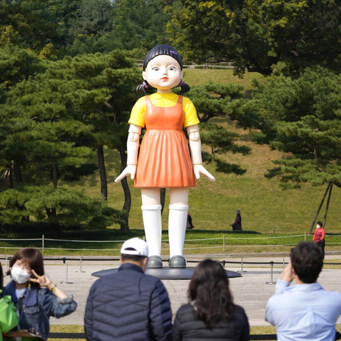 Visitors take photos of a model of the massive doll that was featured in Netflix’s series "Squid Game" displayed at the Olympic Park in Seoul, Oct. 26, 2021.