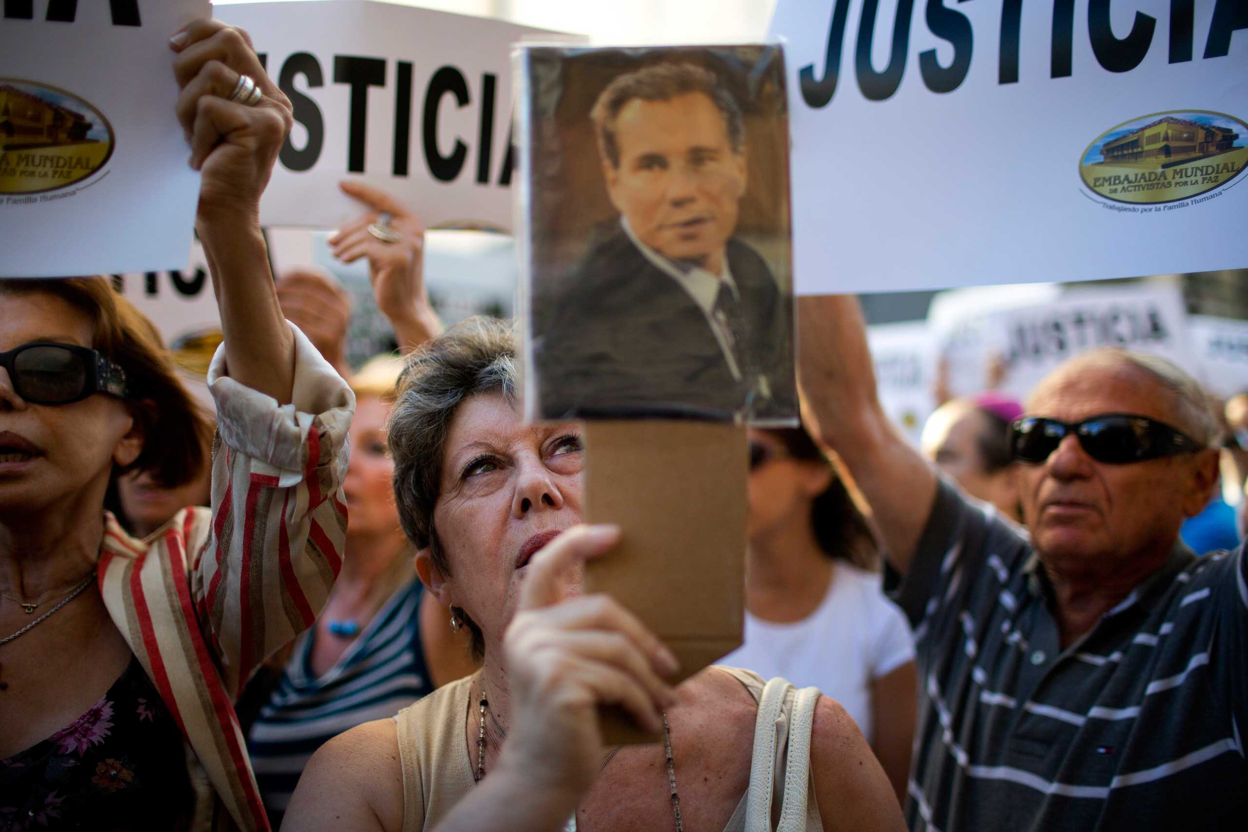 A woman chants the Argentine national anthem holding a portrait of the late prosecutor Alberto Nisman outside the AMIA Jewish community center in Buenos Aires, Jan. 21, 2015.