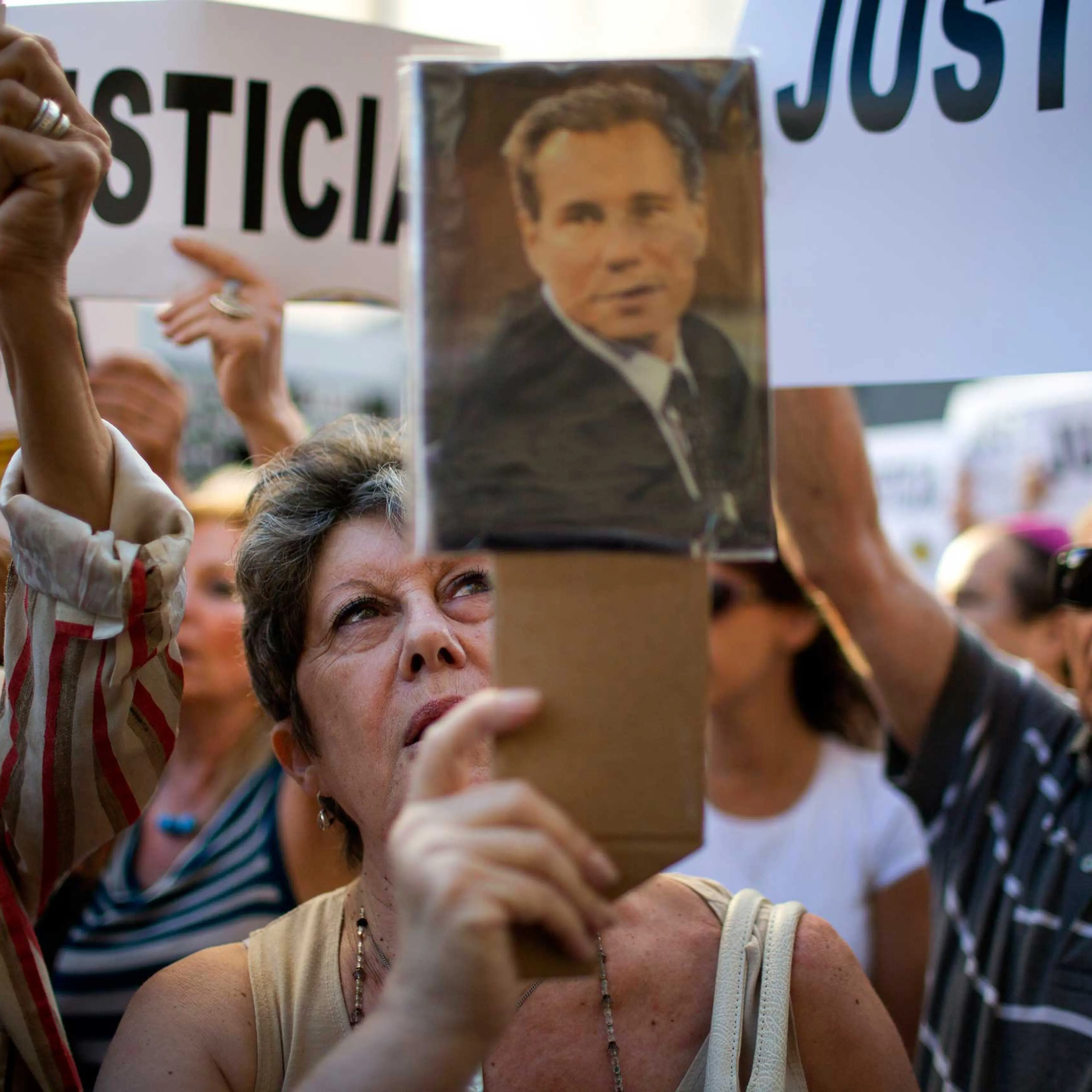 A woman chants the Argentine national anthem holding a portrait of the late prosecutor Alberto Nisman outside the AMIA Jewish community center in Buenos Aires, Jan. 21, 2015.