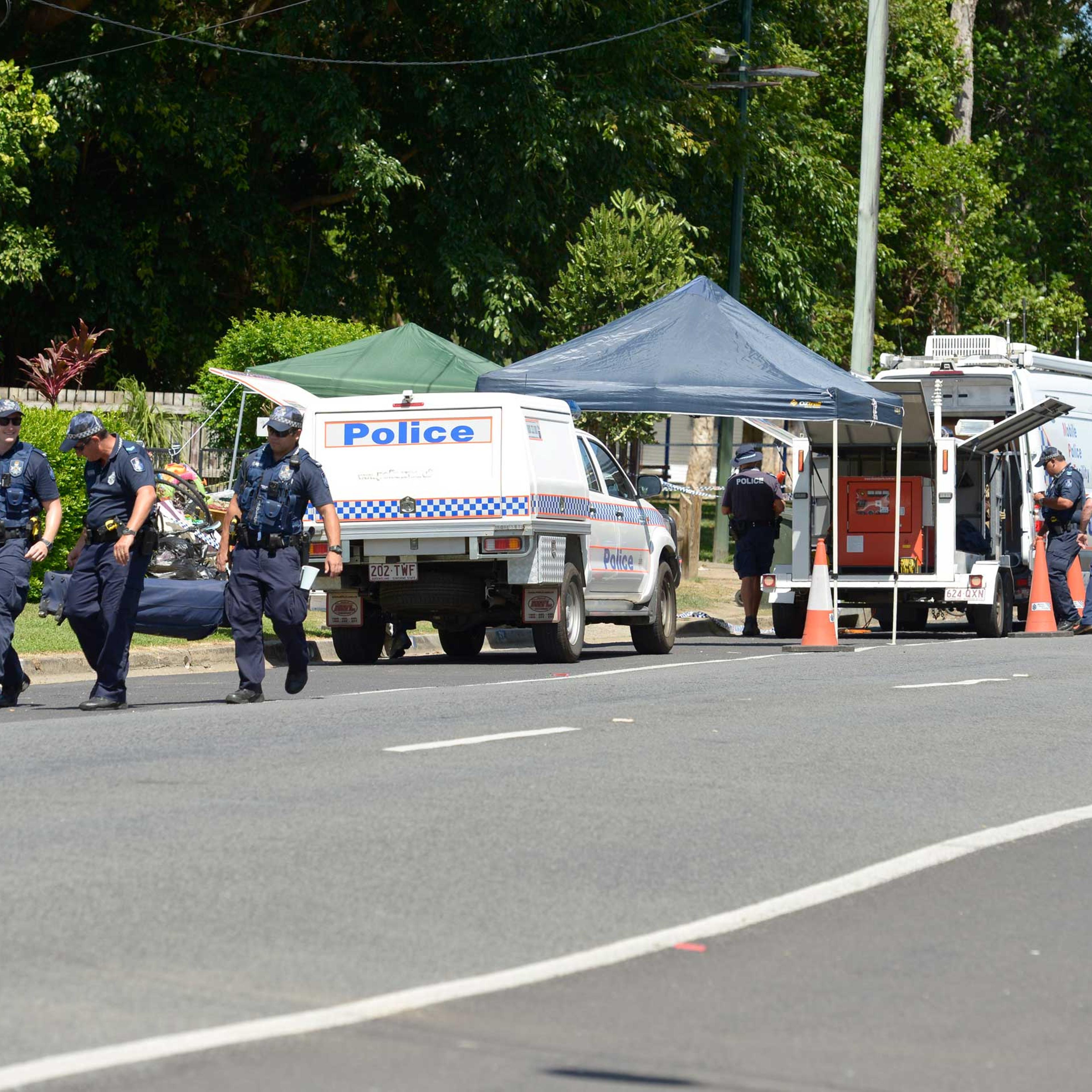 Police carry equipment near a road block outside a house where eight children have been found dead in the Cairns suburb of Manoora, Australia, Friday Dec. 19, 2014.