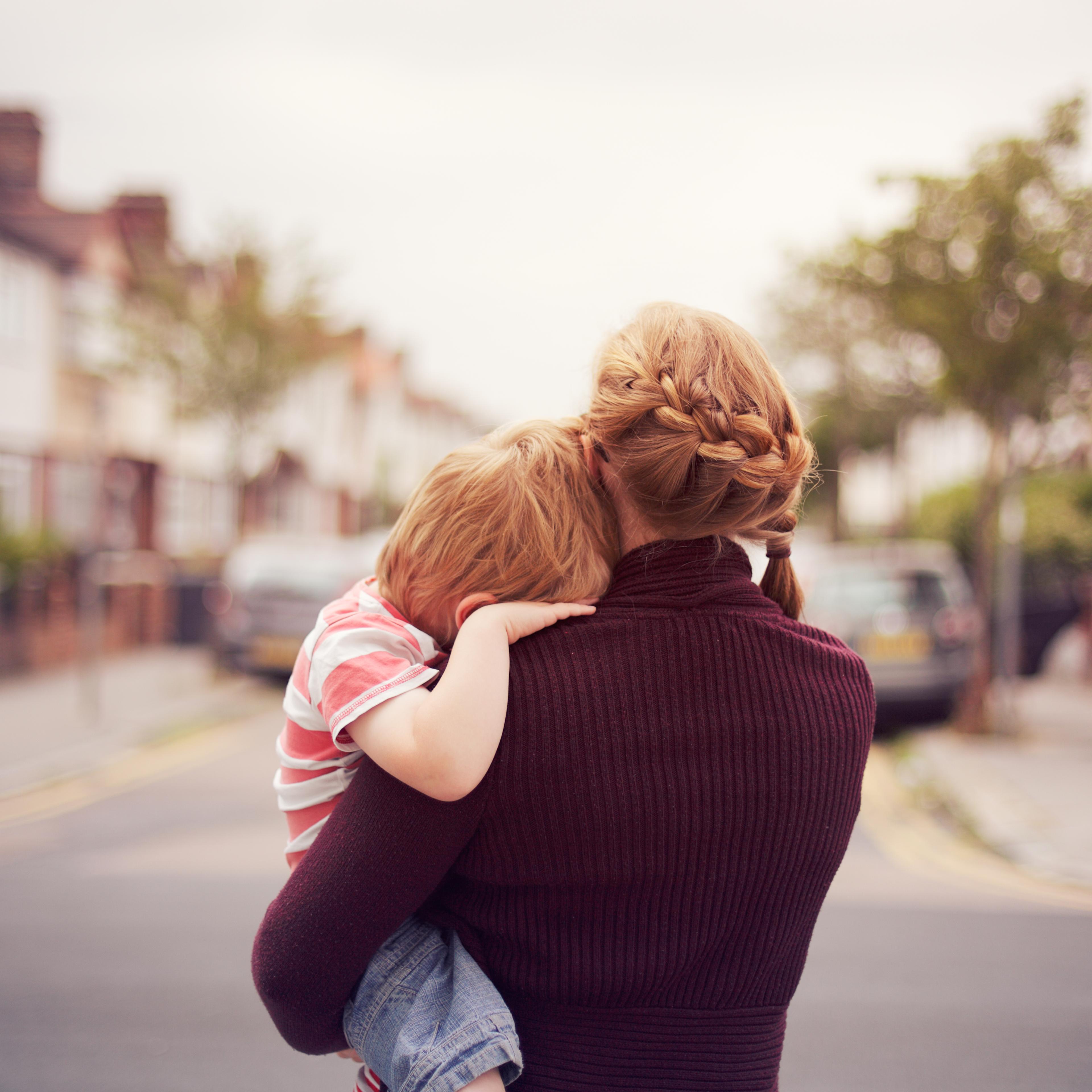 Young boy resting on mother's shoulder