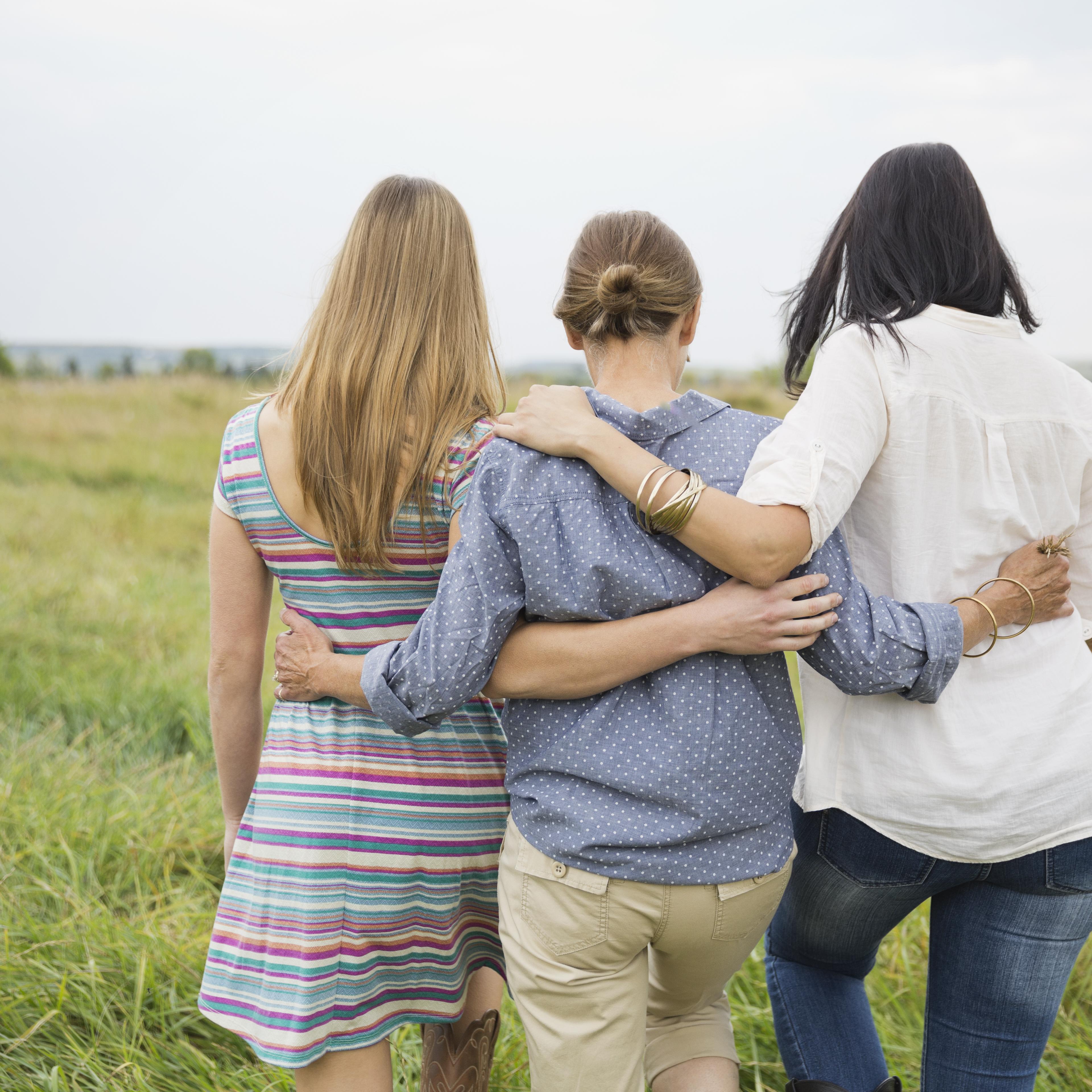 Rear view of female family members walking through field