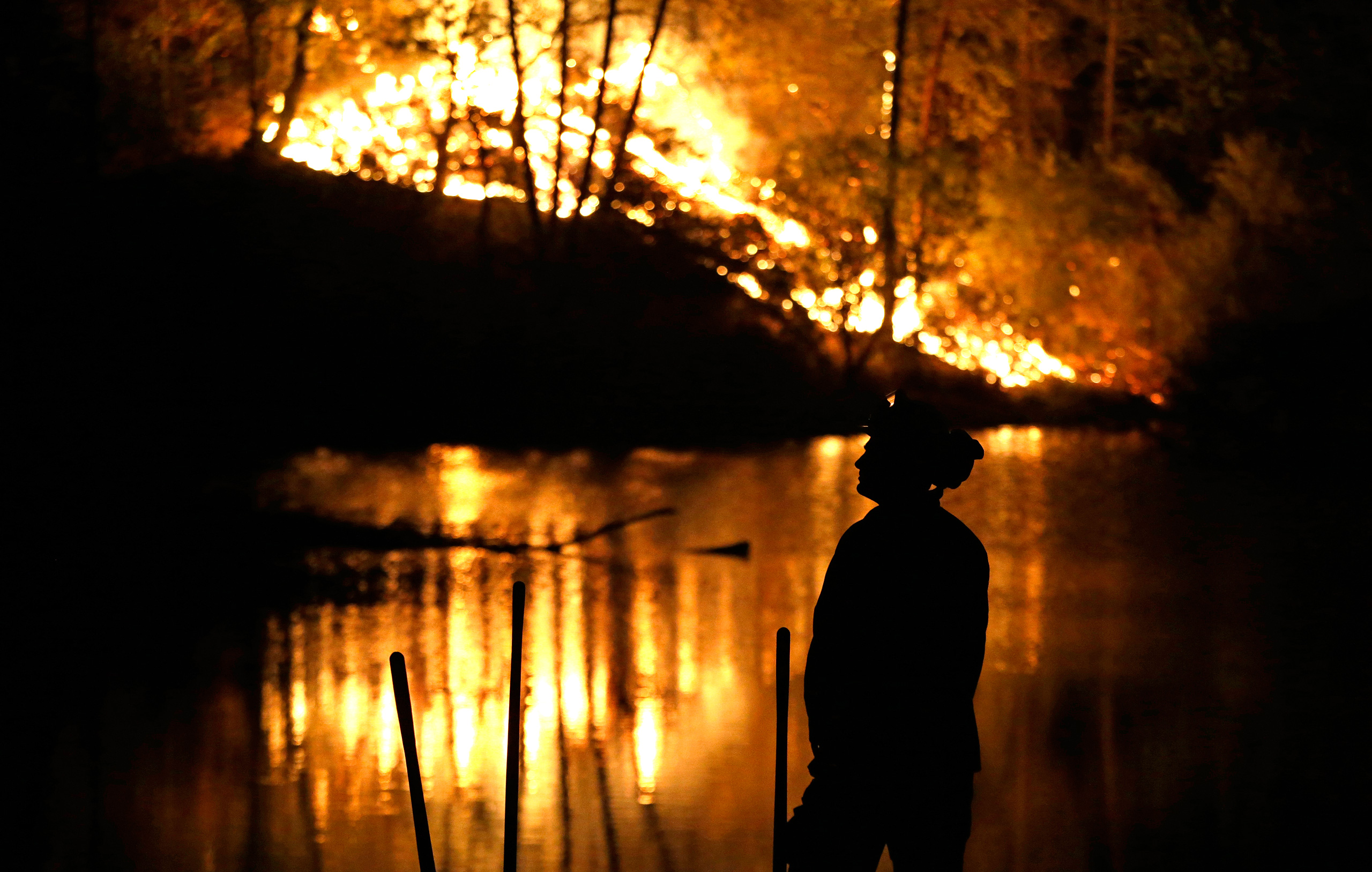 A firefighter stands near a wildfire in Middletown, Calif., on Sunday, Sept. 13, 2015. Two of California's fastest-burning wildfires in decades overtook several Northern California towns, killing at least one person and destroying hundreds of homes and b