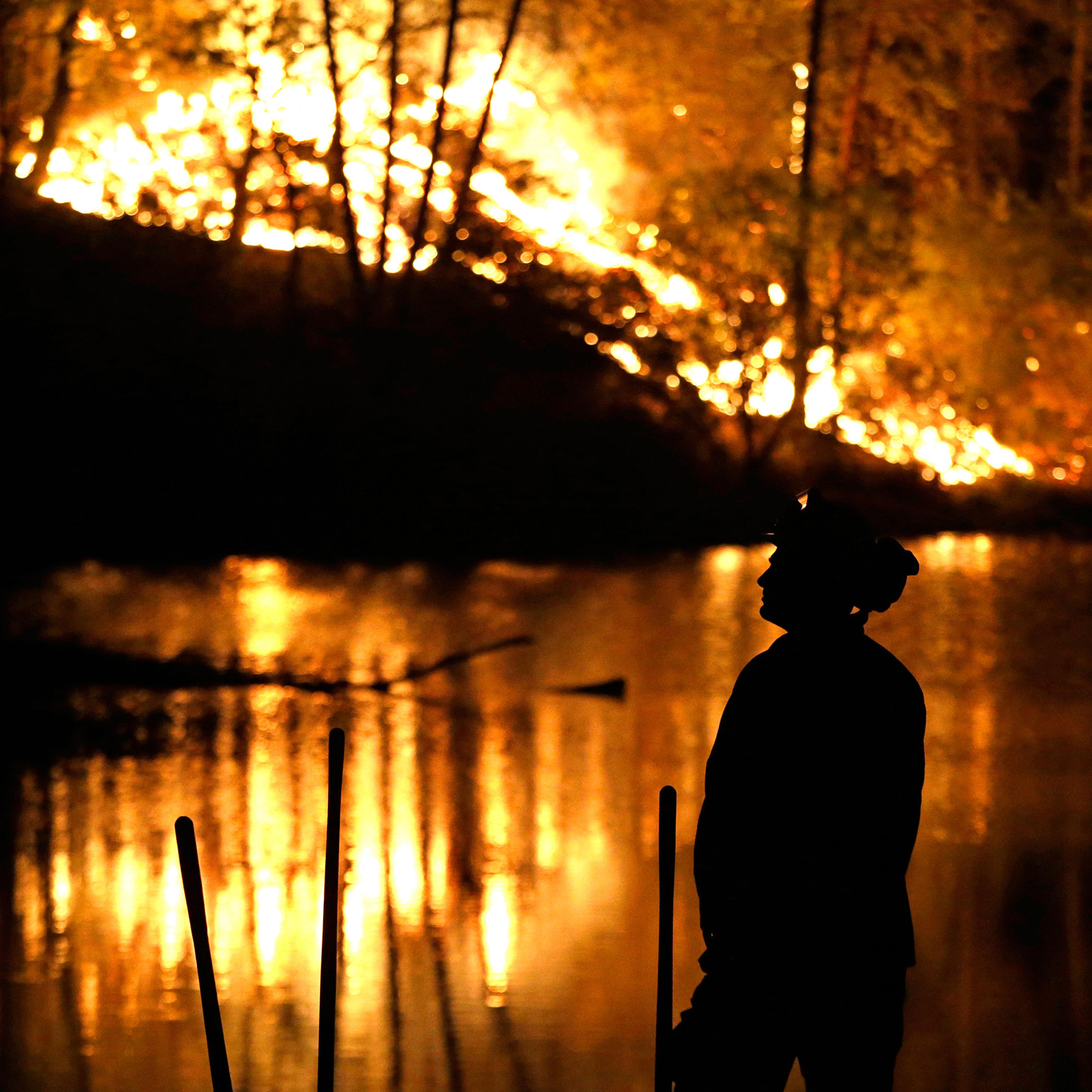 A firefighter stands near a wildfire in Middletown, Calif., on Sunday, Sept. 13, 2015. Two of California's fastest-burning wildfires in decades overtook several Northern California towns, killing at least one person and destroying hundreds of homes and b