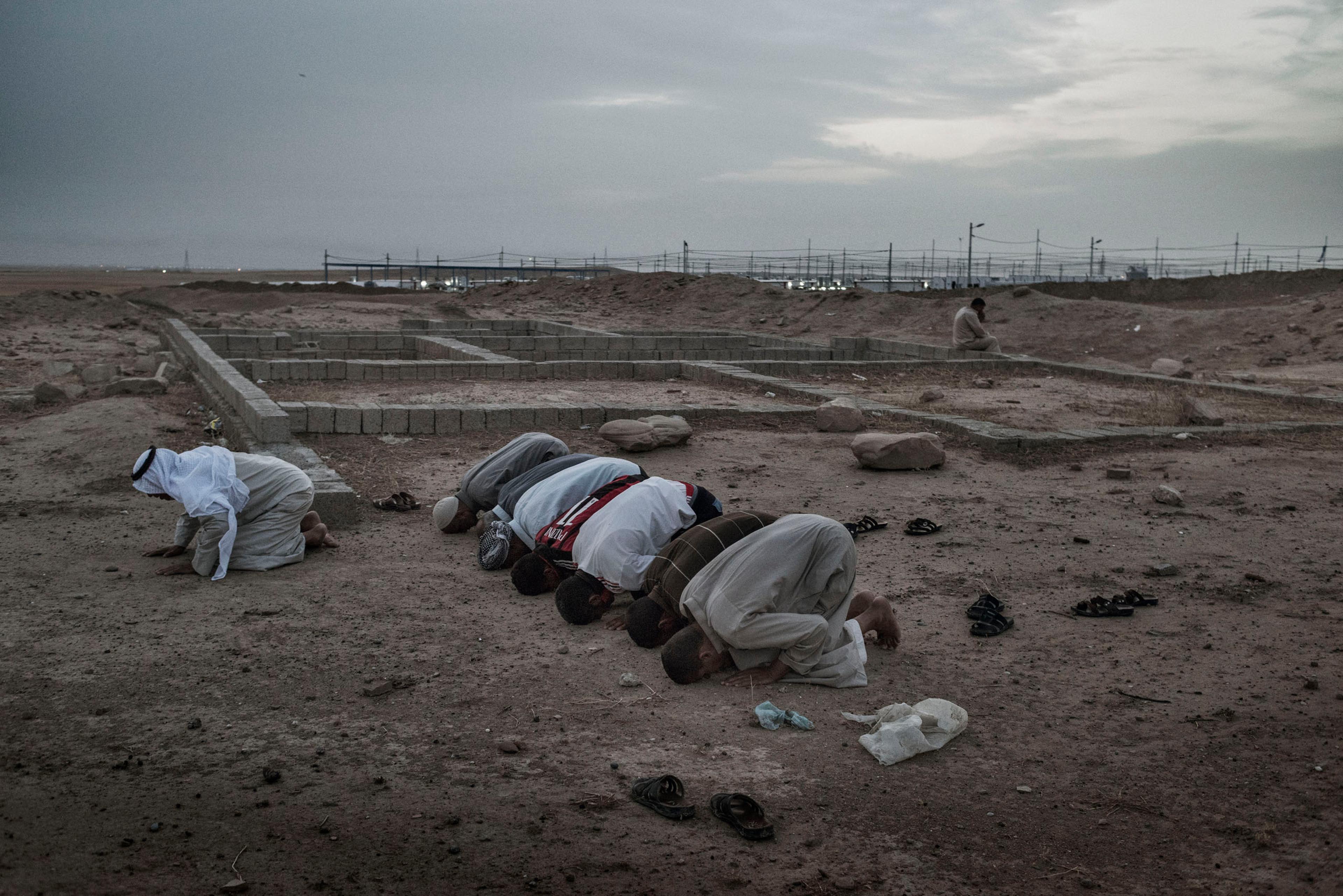 Men pray outside a camp for internally displaced people (IDP's) near the Iraqi town of Makhmour, May 17, 2016. The United Nations said in April that as many as 30,000 people could be forced to flee instability in the Makhmour area, as the Iraqi military