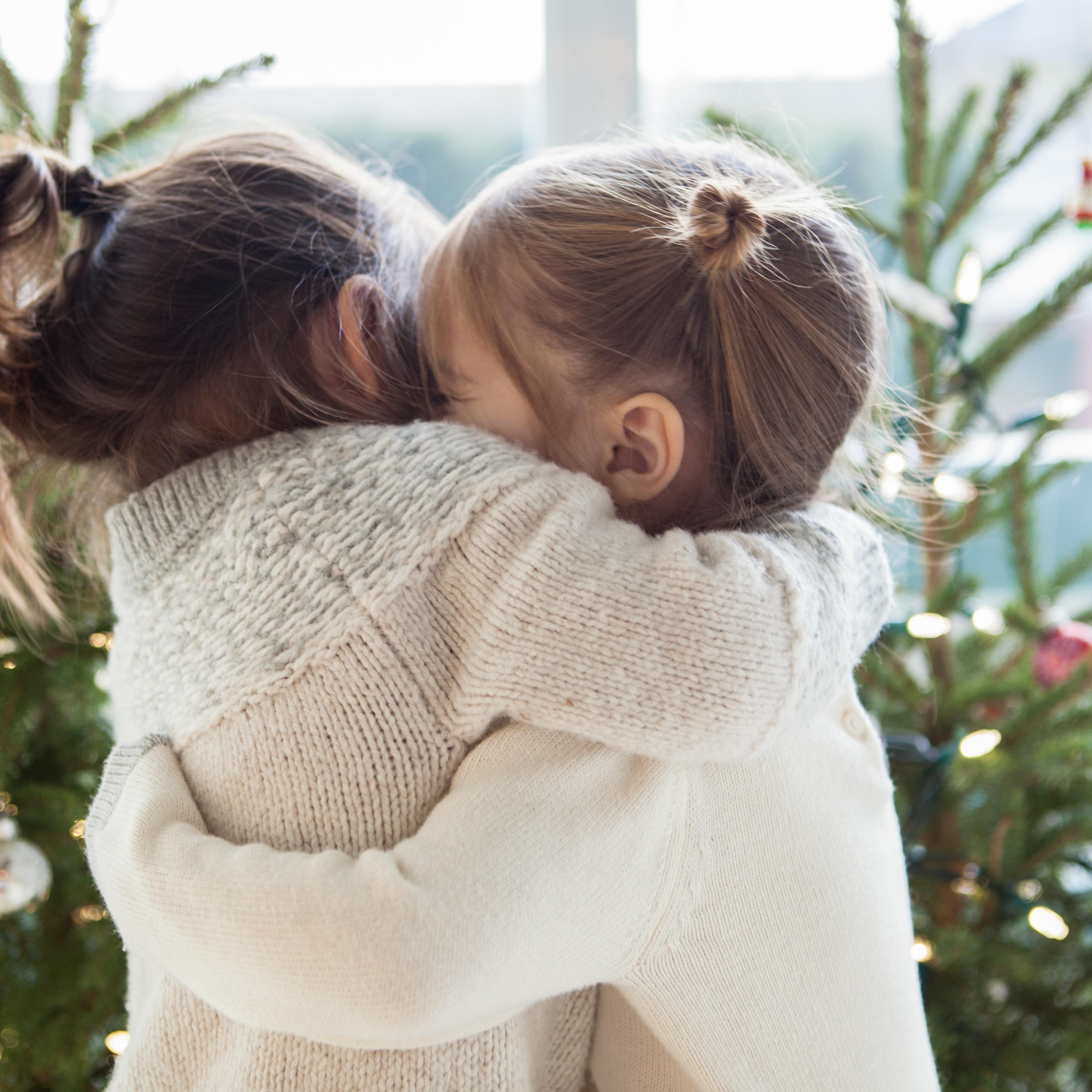 Girls hugging in front of Christmas trees