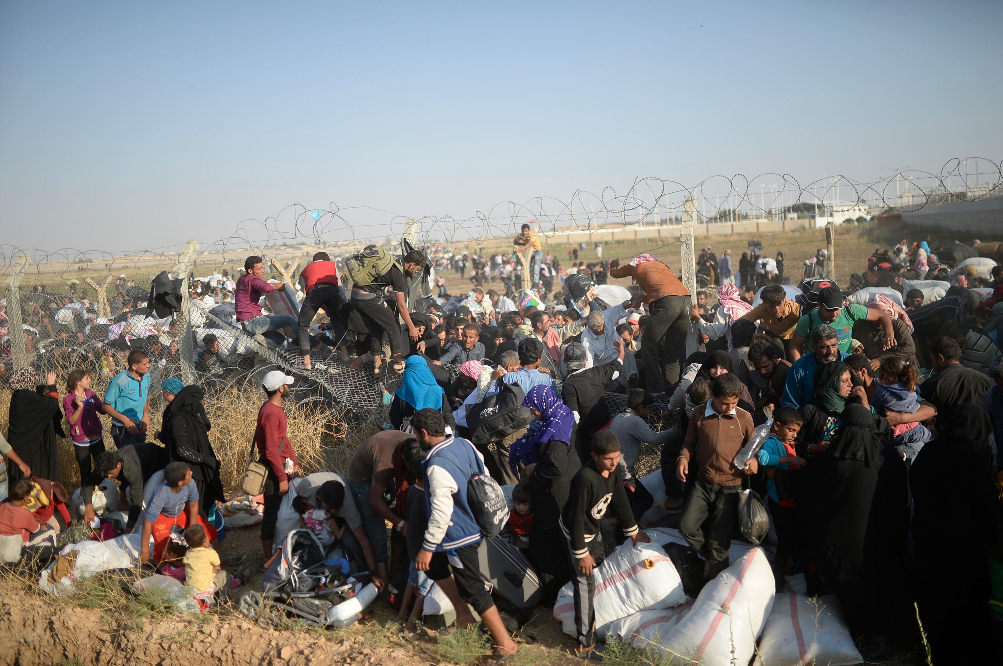 Thousands of Syrians break through the ripped fences, crossing illegally from the Syrian town of Tell Abyad into the Turkish crossing gate in Akçakale, in the Şanlıurfa province. June 14, 2015.