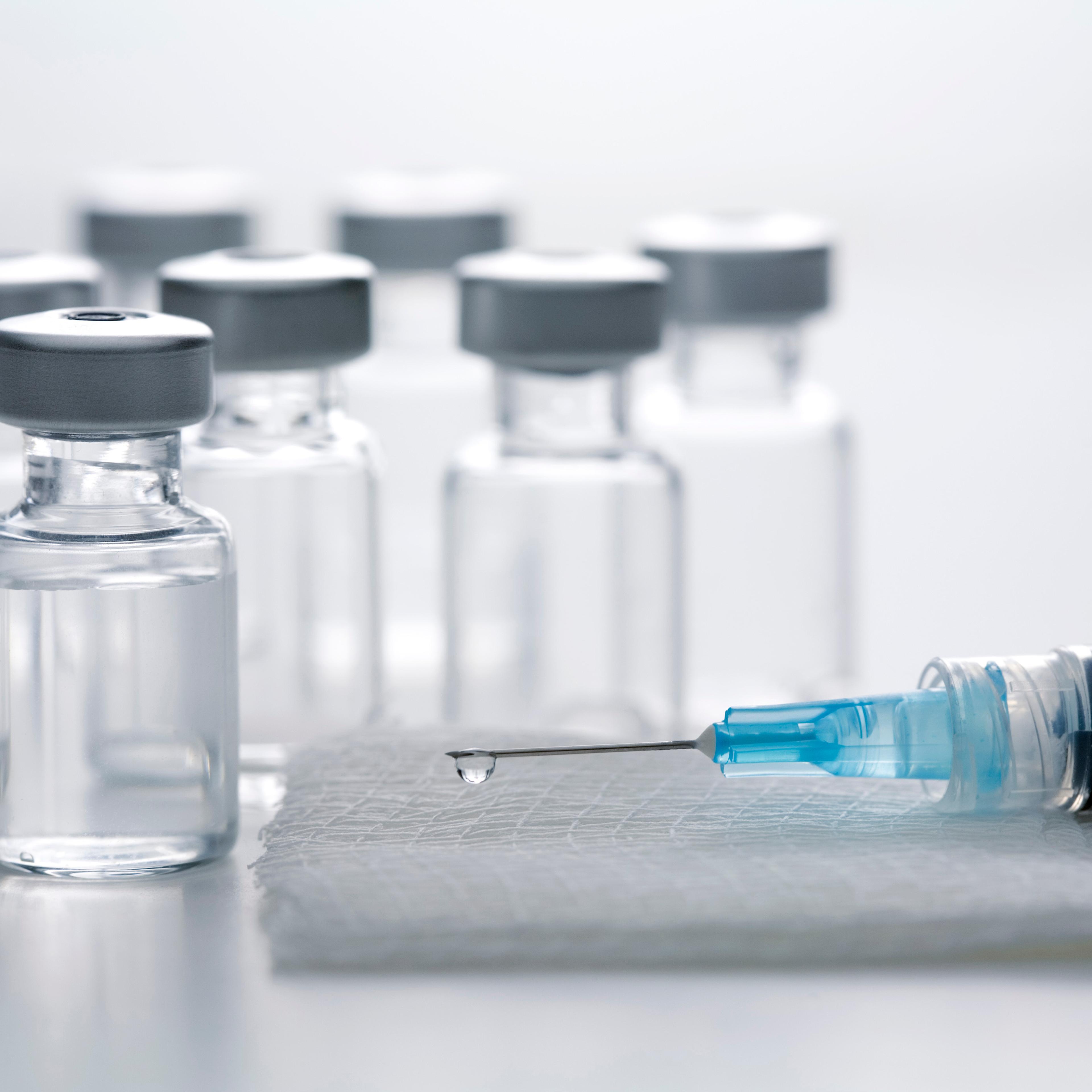 Syringe on gauze pad with vaccine bottles