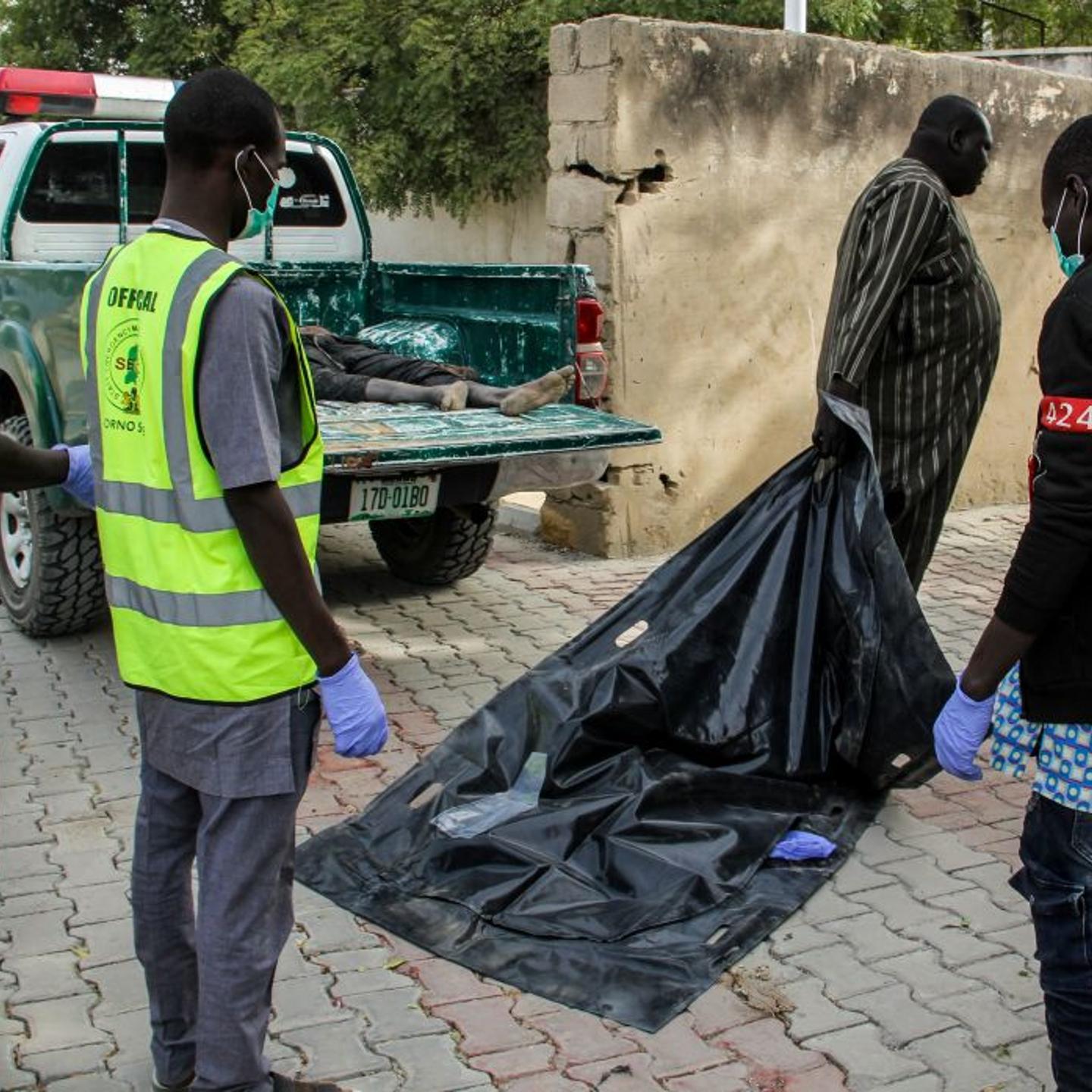 Officials load the body of a victim to the general hospital mortuary
