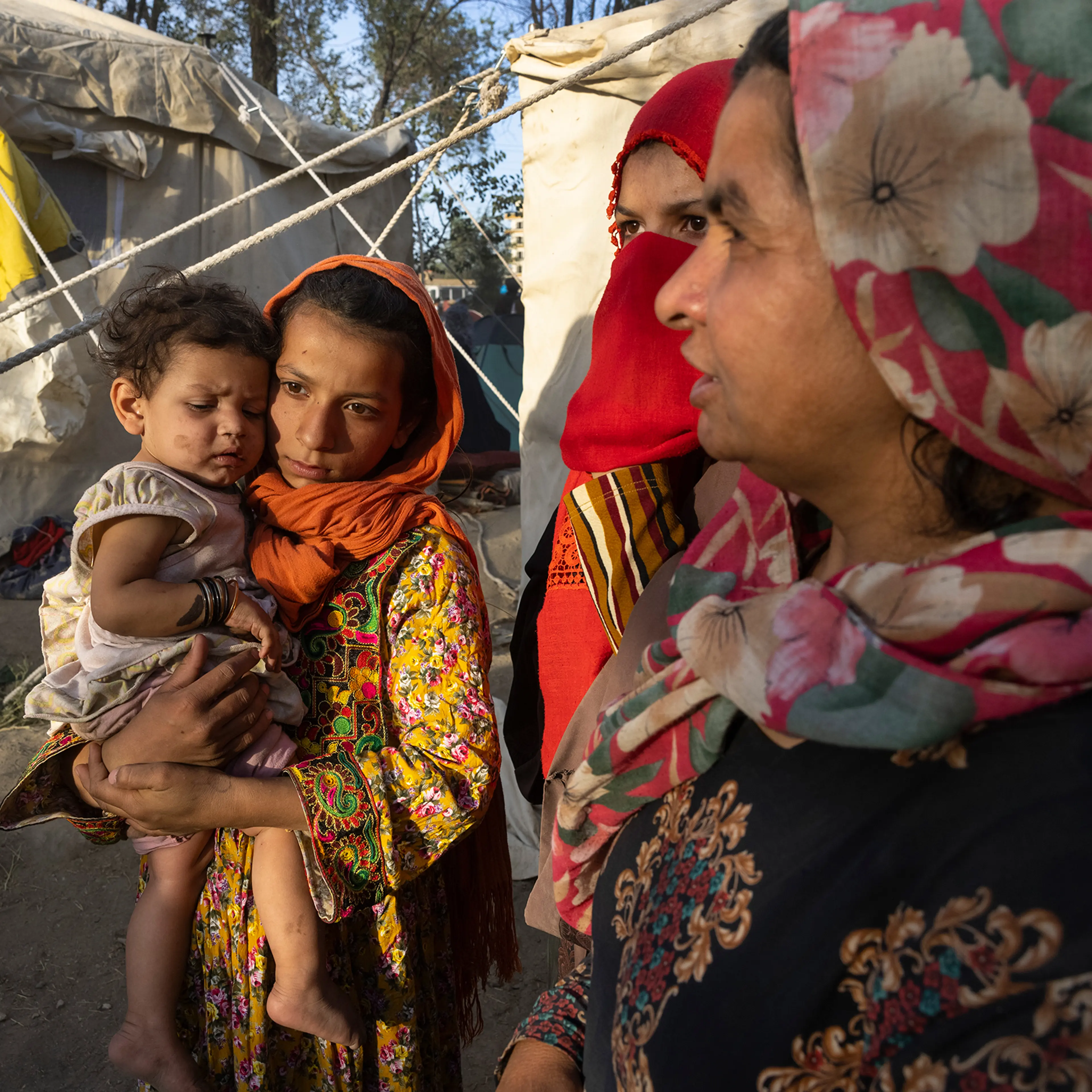 Halida, an 11-year-old whose father was killed by the Taliban, holds her eight-month-old cousin, Shafika, alongside family members as Afghans from the northern provinces arrive at a makeshift camp in Kabul on Aug. 10, 2021. Five days later, the Taliban t