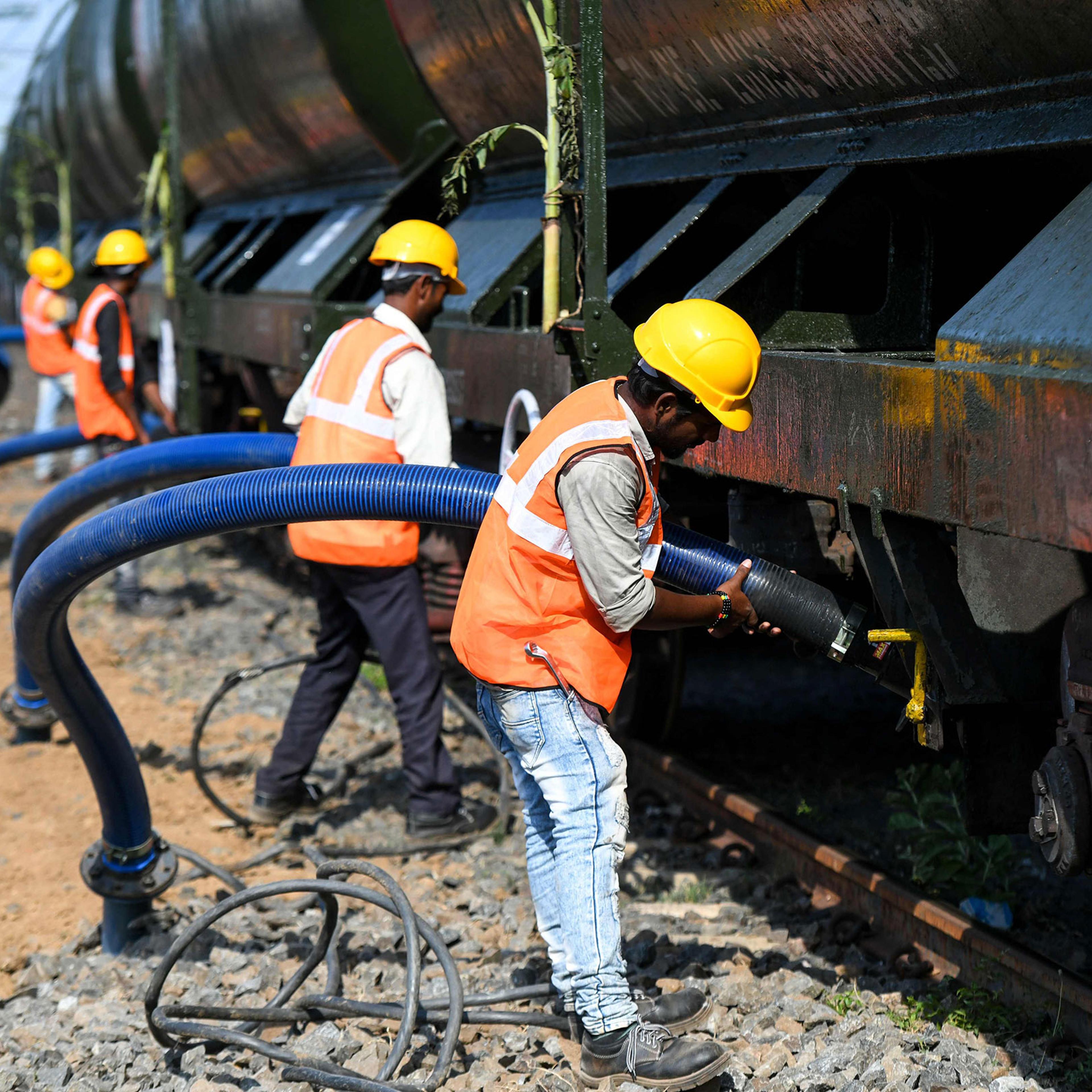 Indian laborers connect pipes to collect water from a train carrying liters of water at a railway station in Chennai on July 12.
