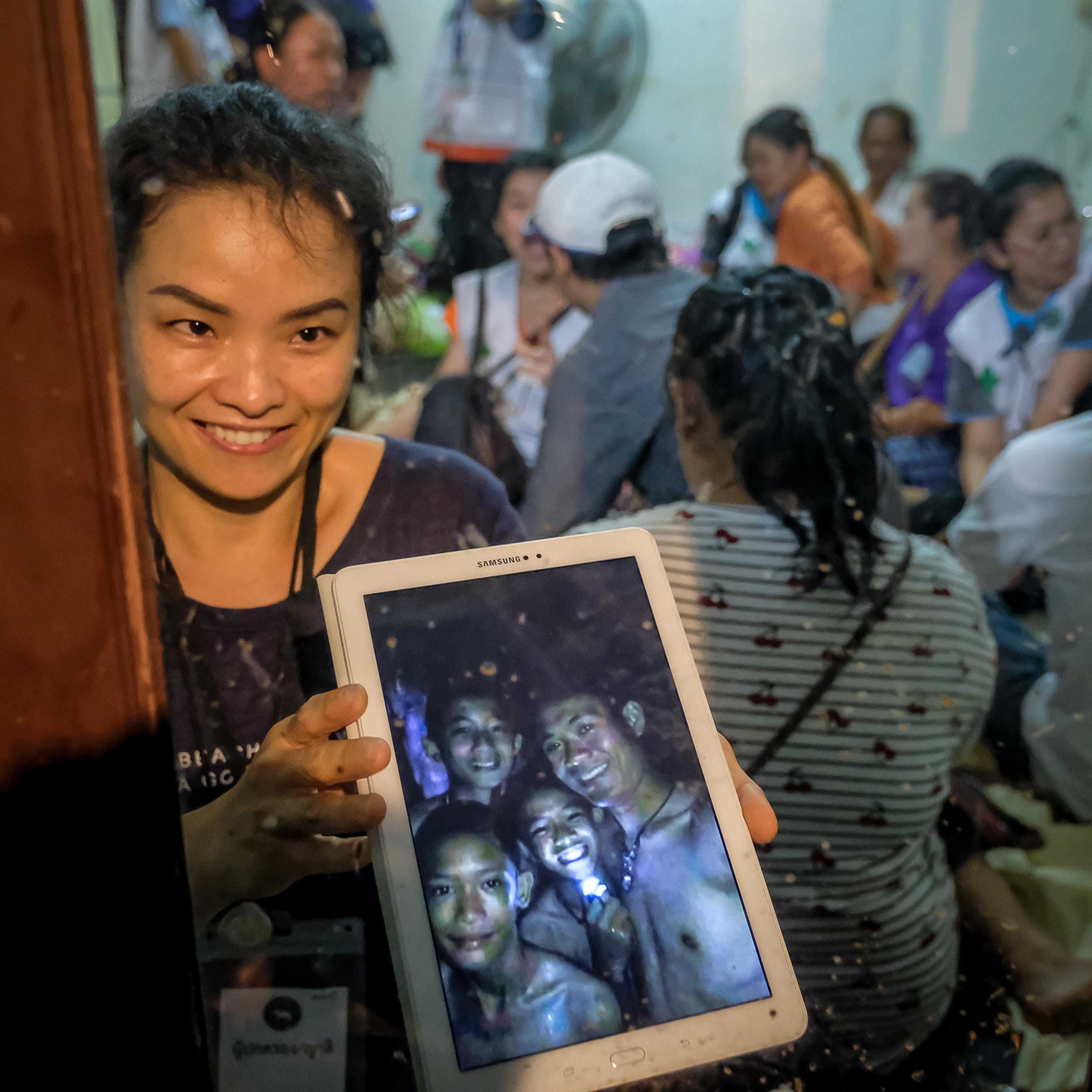 Relatives of the missing boys show photos of them after the 12 boys and their soccer coach have been found alive in the cave where they've been missing for over a week after monsoon rains blocked the main entrance on July 2, 2018 in Chiang Rai, Thailand.