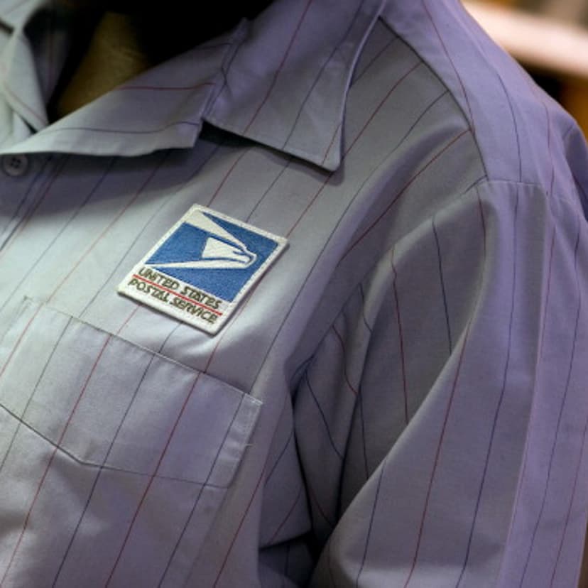 The U.S. Postal Service (USPS) logo is seen on the shirt of a letter carrier.