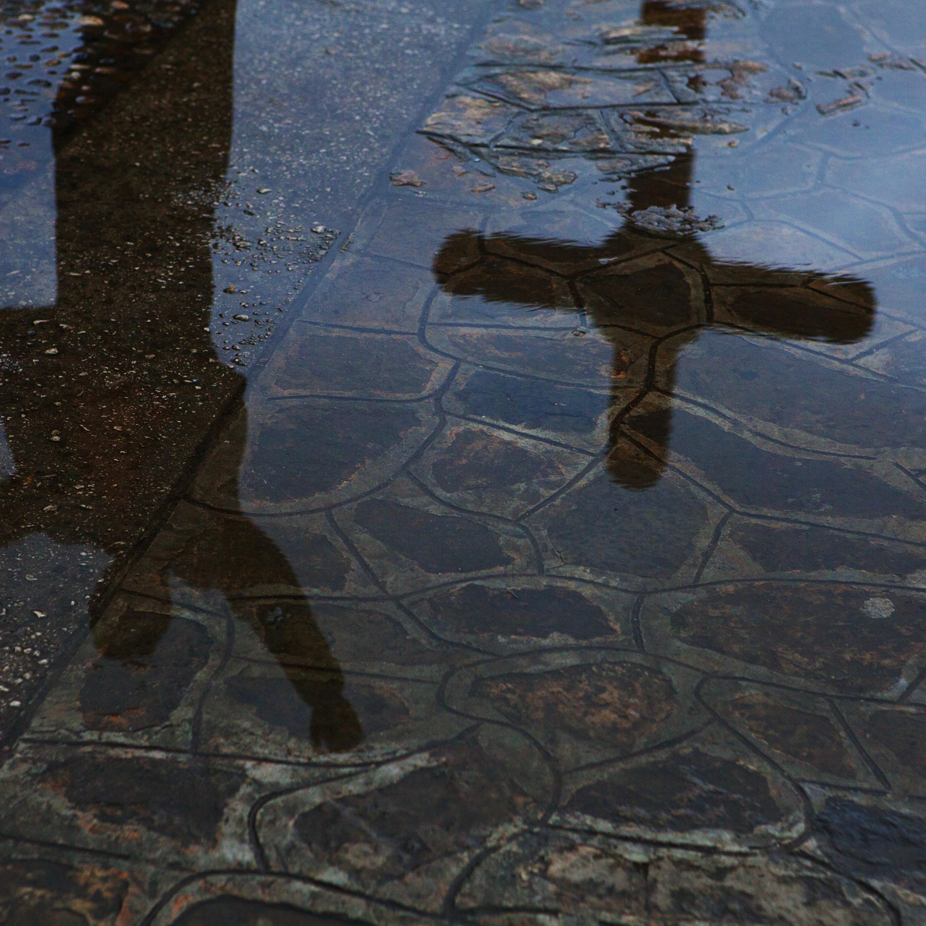 Reflection of man and crucifix in city puddle