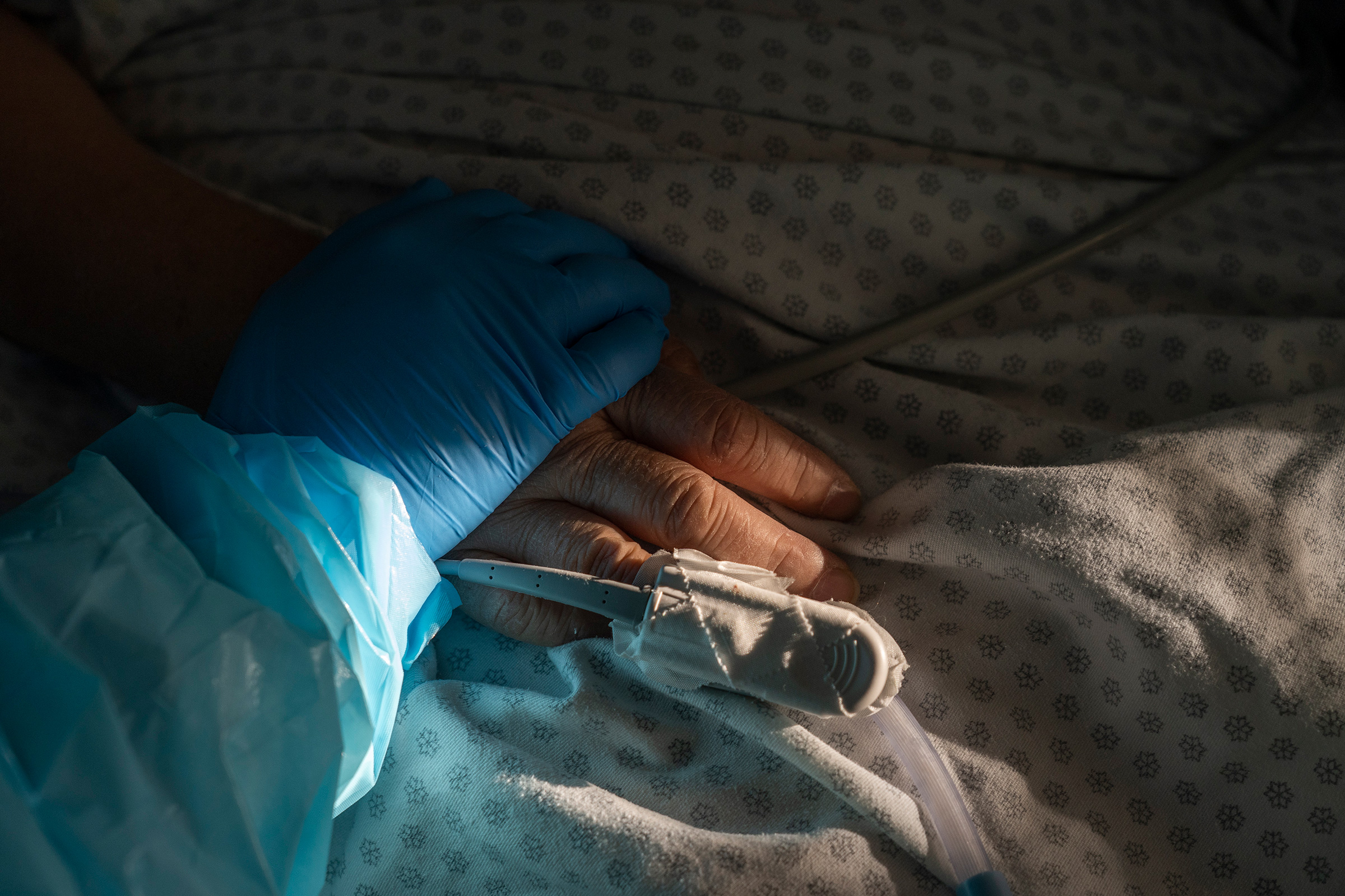 Medical staff member Tanna Ingraham holds the hand of a patient in the COVID-19 intensive care unit (ICU) at the United Memorial Medical Center in Houston, on Dec. 21.