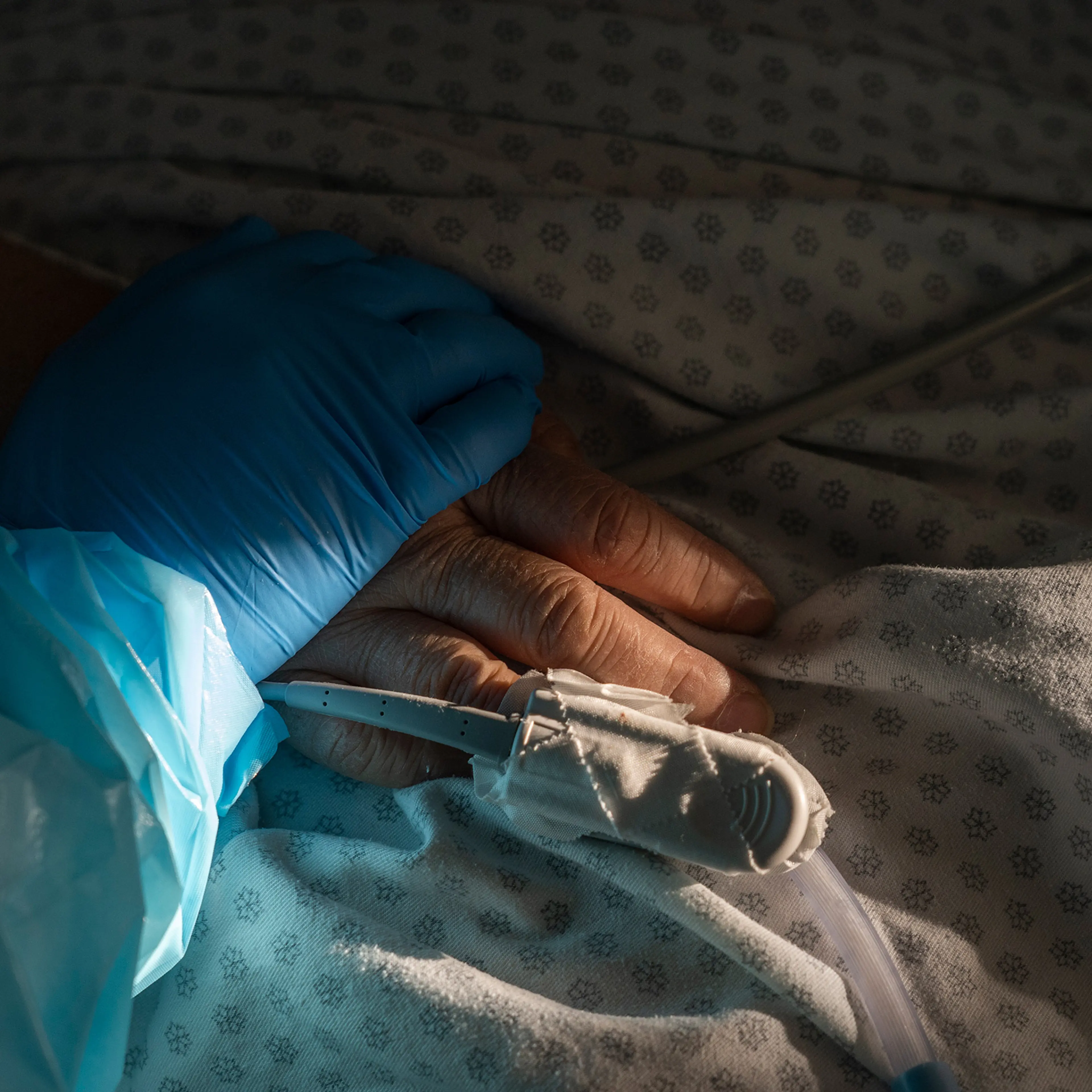 Medical staff member Tanna Ingraham holds the hand of a patient in the COVID-19 intensive care unit (ICU) at the United Memorial Medical Center in Houston, on Dec. 21.
