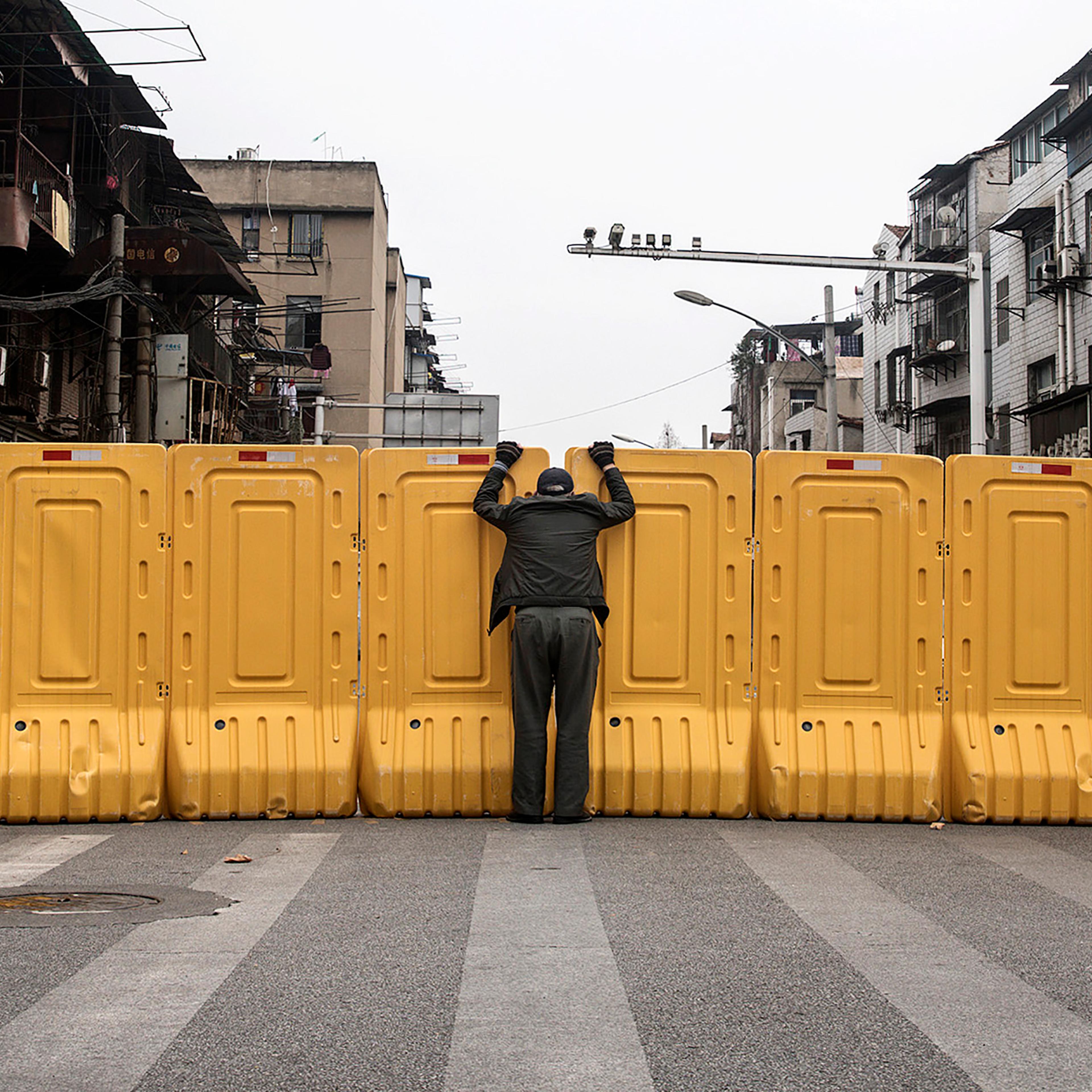 A man talks to another man through a makeshift barricade, built to control entry and exit to a residential compound, in Wuhan, China, on March 8.