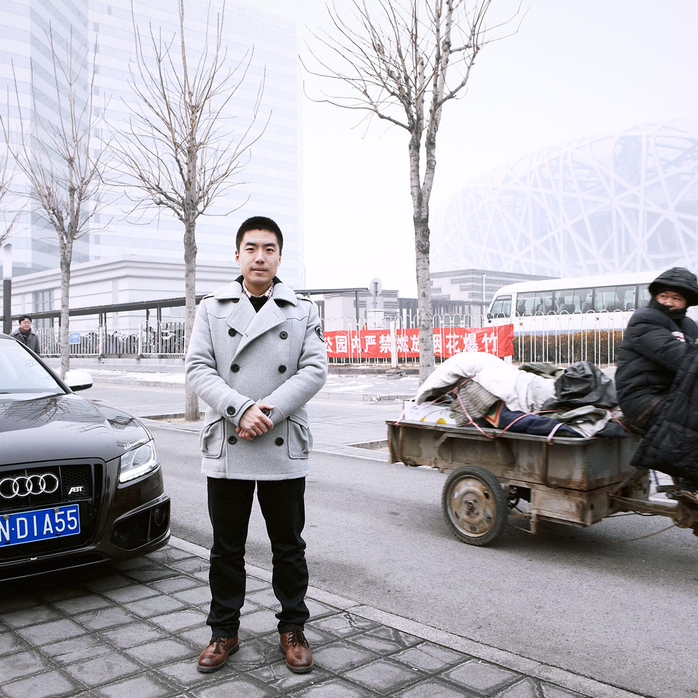 Zhao Xiadi next to his Audi A5 with National Stadium in the background. Beijing, China, Chaoyang District. February 15, 2014