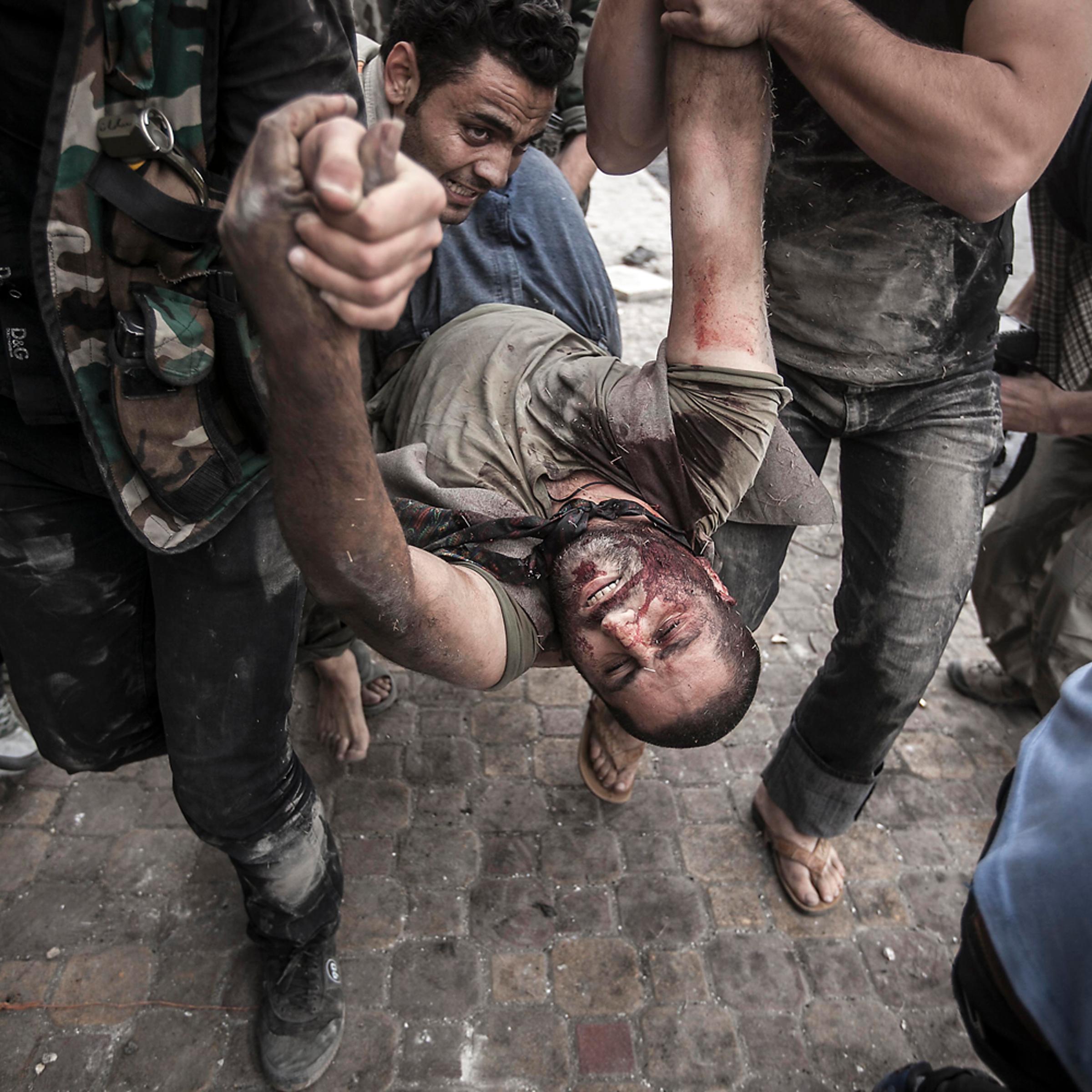 Image: Oct. 20, 2012. A Free Syrian Army fighters carry a civilian away from the line of fire after he was shot twice by a Syrian army sniper in Aleppo, Syria.