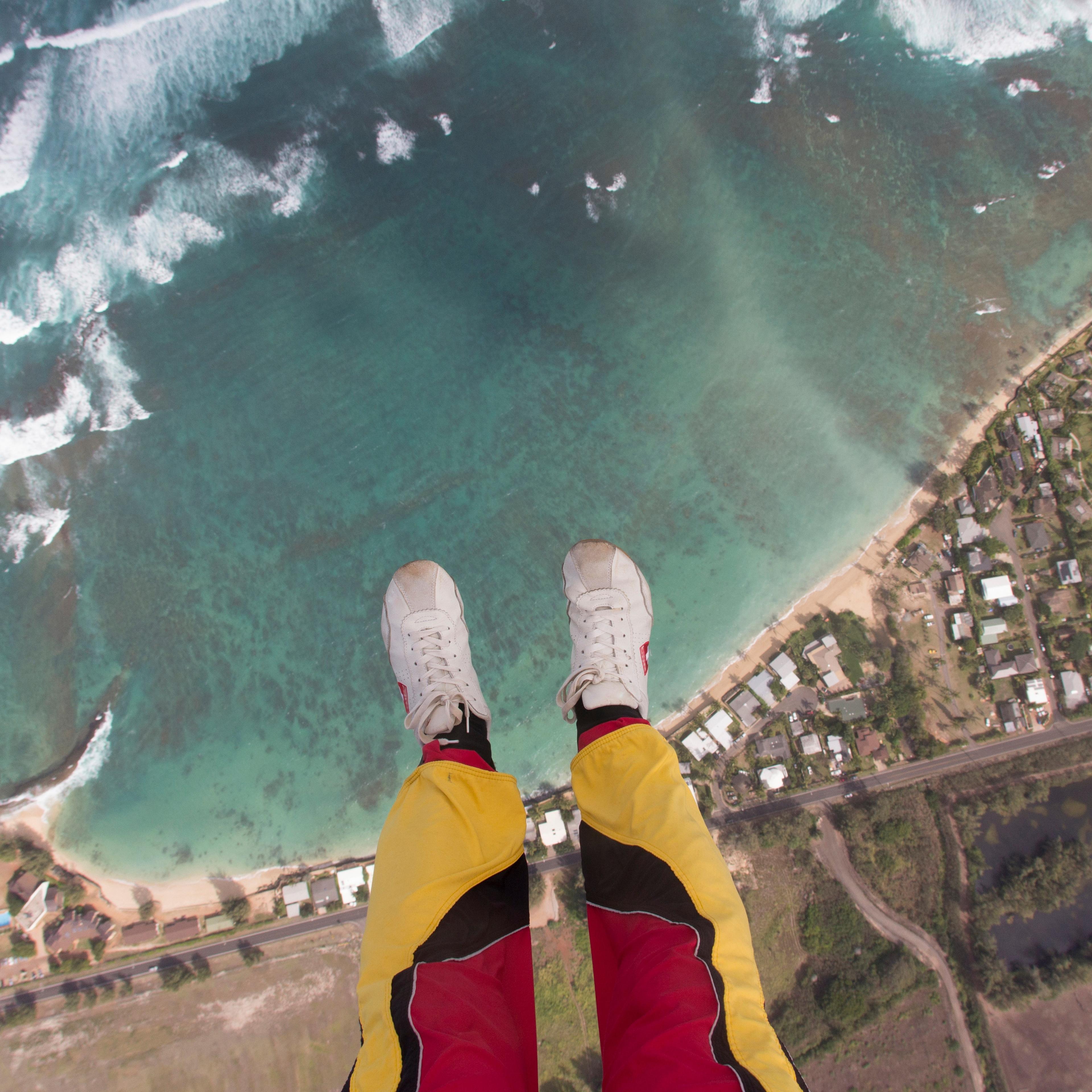 Legs and feet of skydiver above coastline