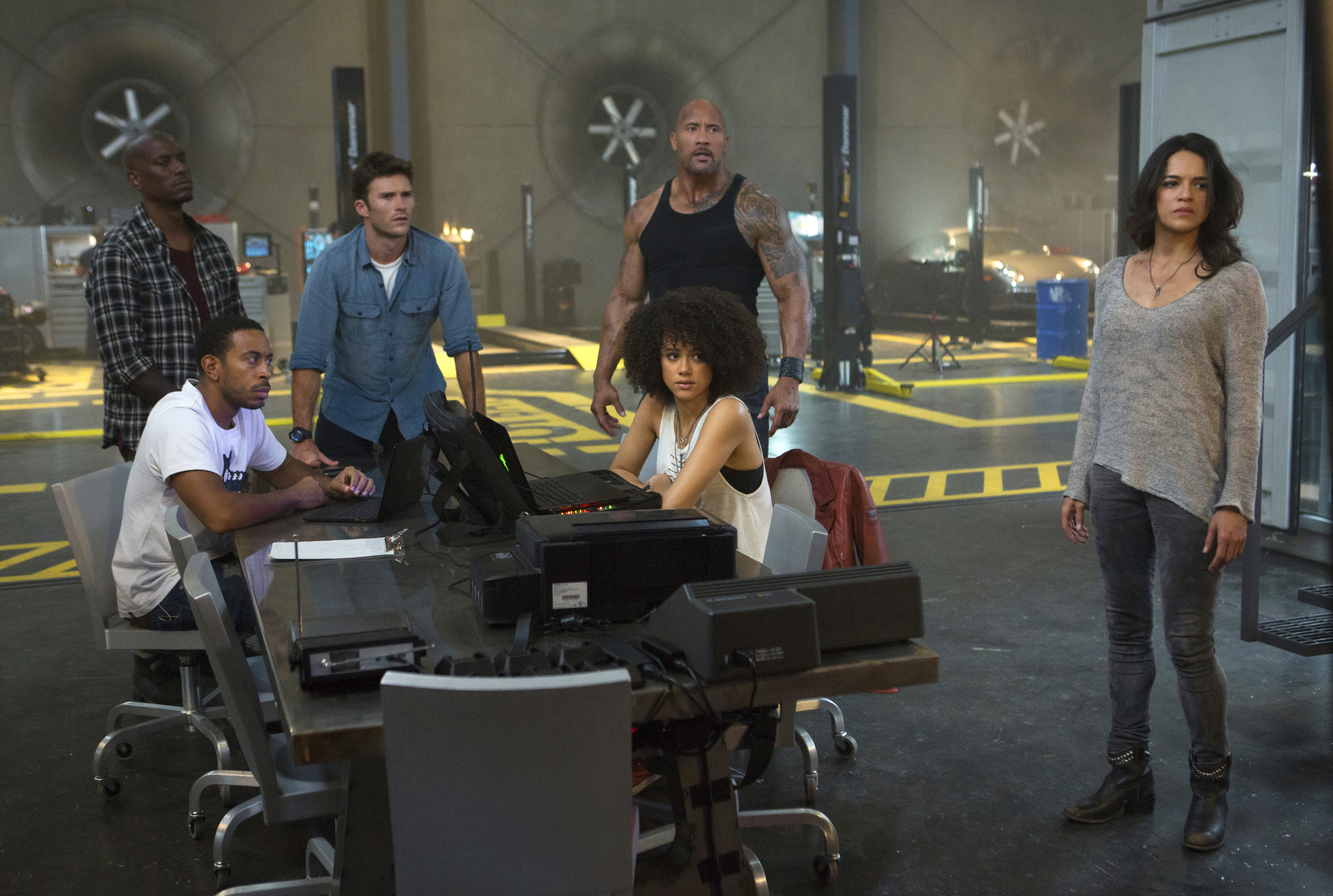 Chris "Ludacris" Bridges, seated left, and Nathalie Emmanuel, seated right, and Tyrese Gibson, standing from left, Scott Eastwood, Dwayne Johnson and Michelle Rodriguez in "The Fate of the Furious."