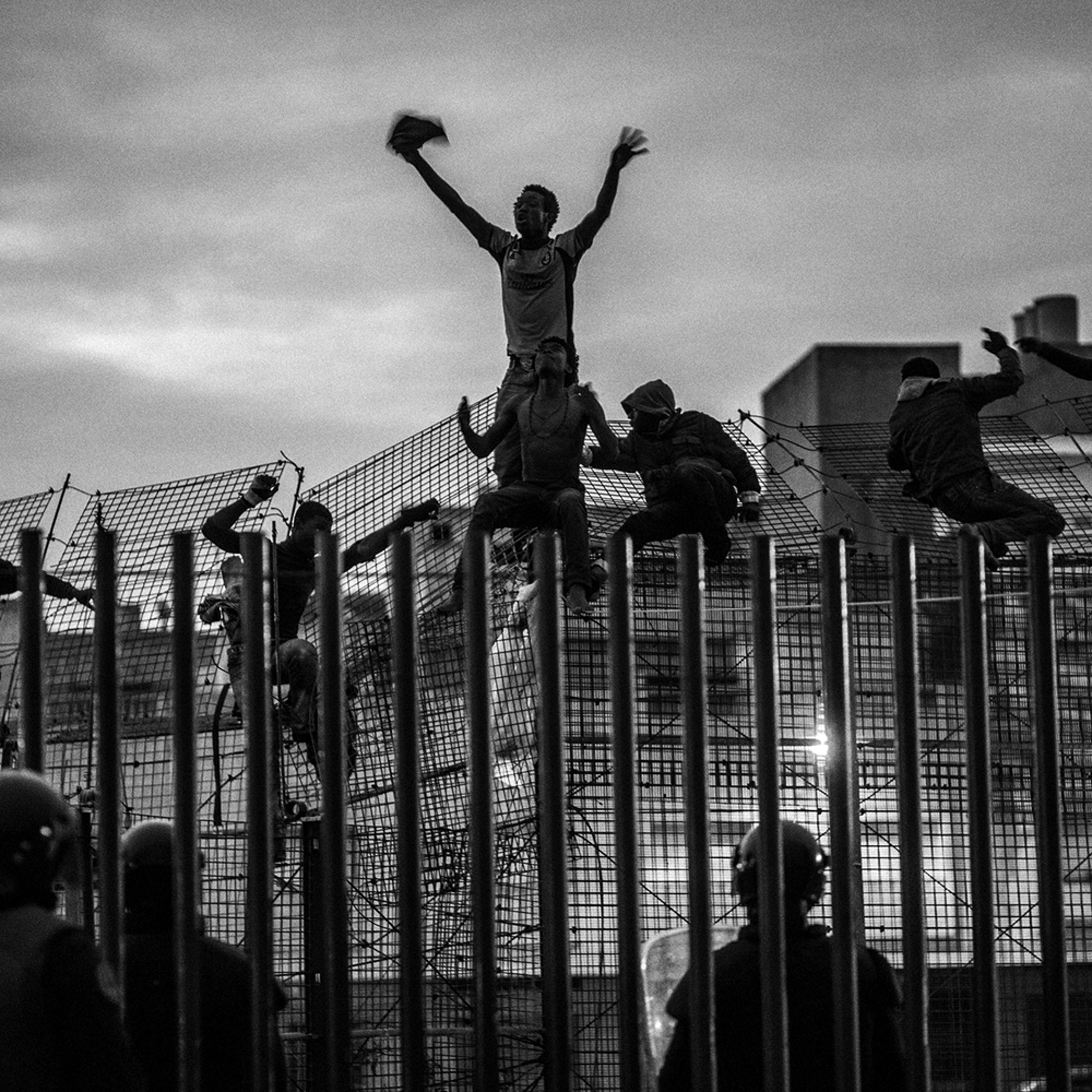 African migrants try to cross a border fence and enter the Spanish enclave of Melilla, March, 2014.