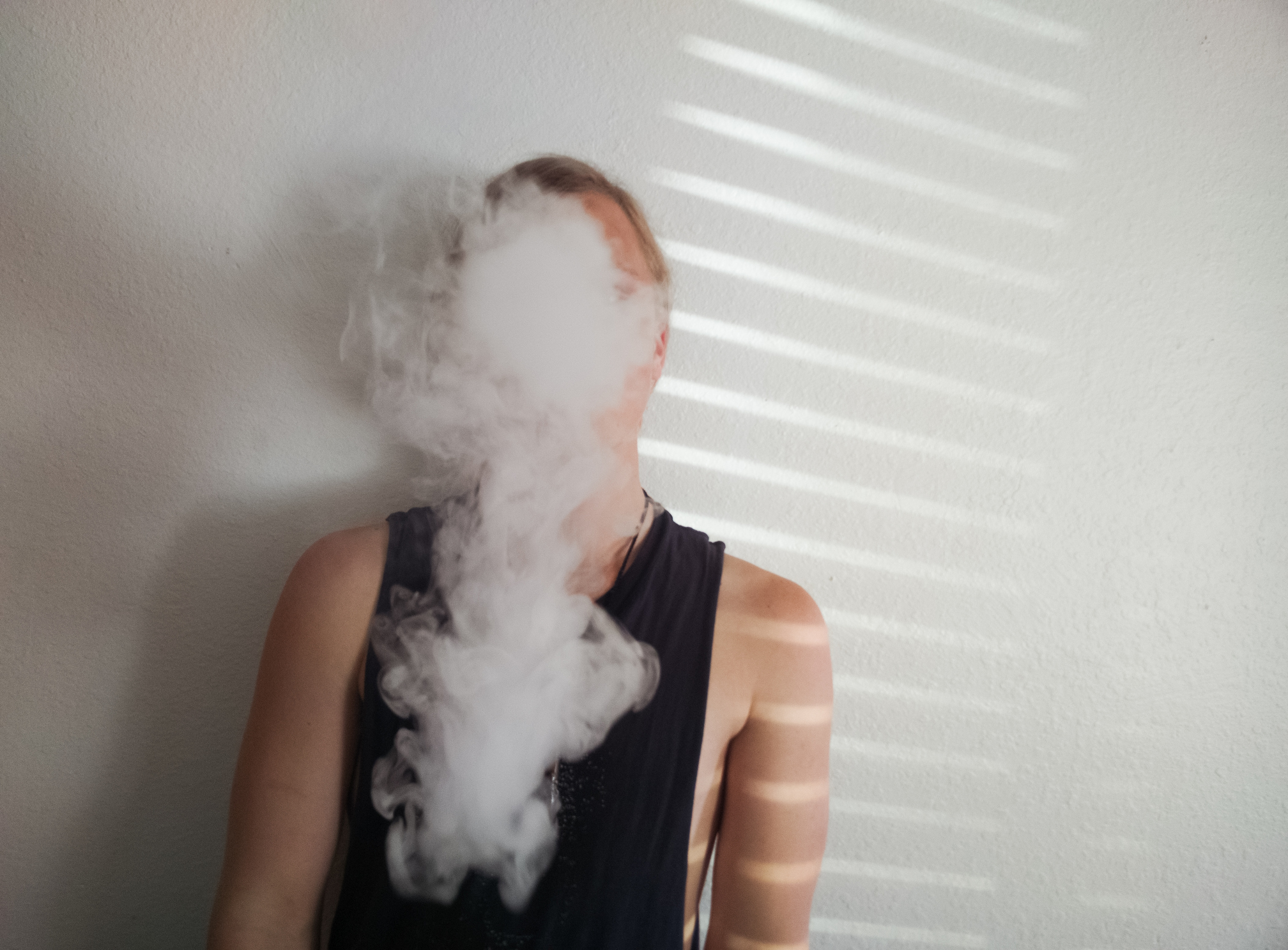 Young man vaping by a wall