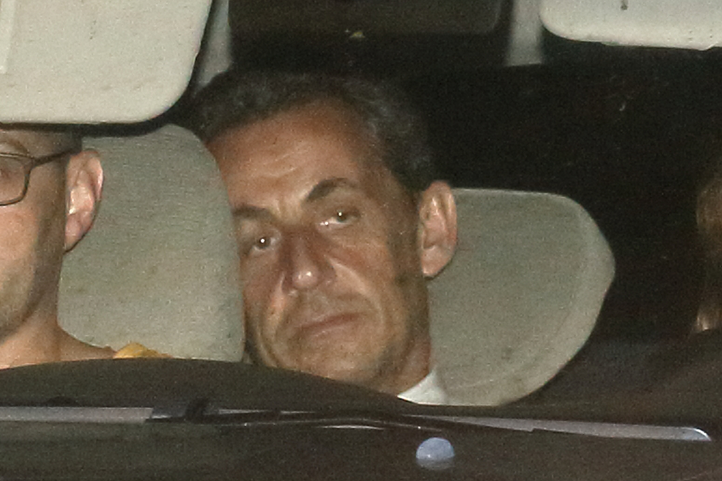 Former French President Nicolas Sarkozy arrives with police by car at the financial investigation unit in Paris to be presented to a judge