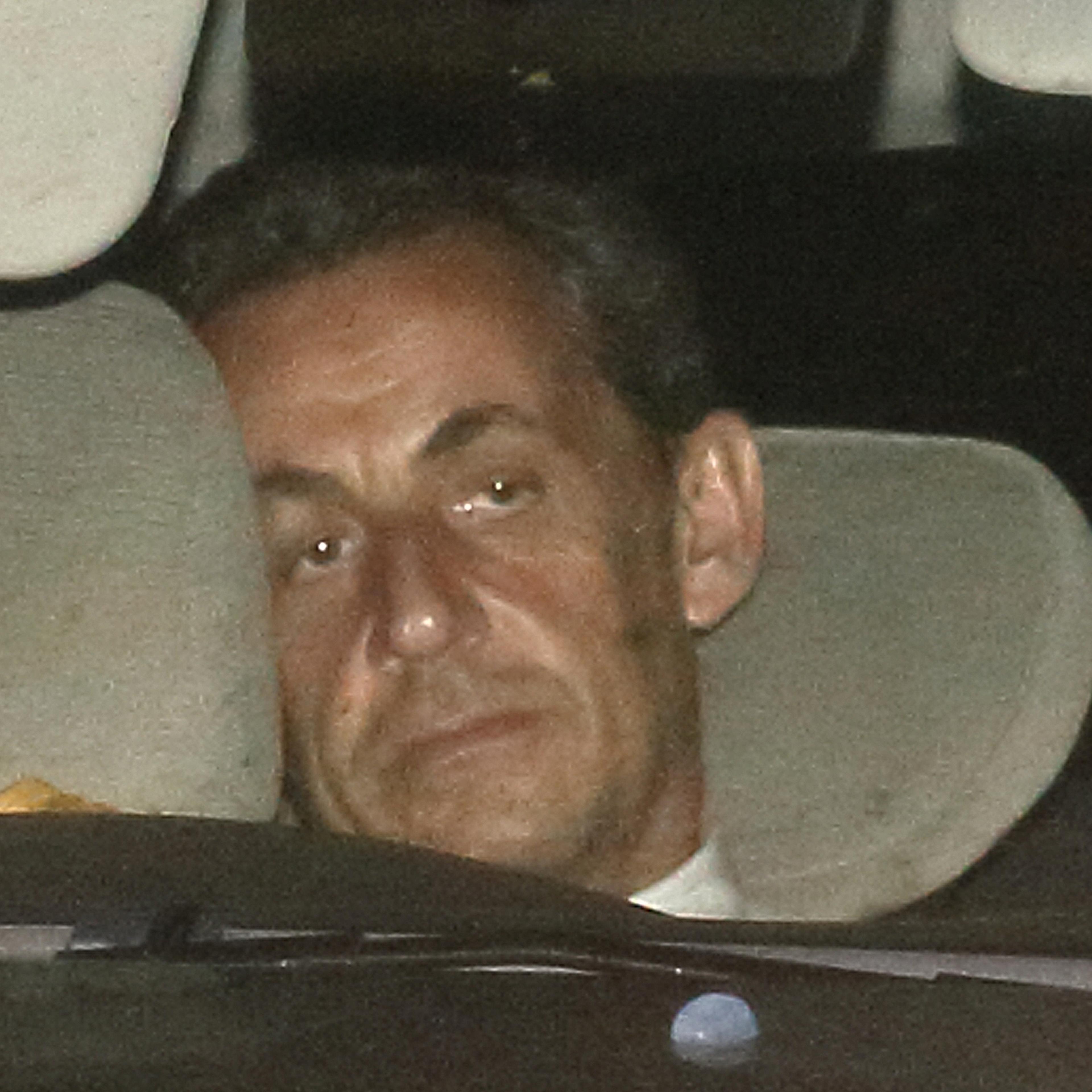 Former French President Nicolas Sarkozy arrives with police by car at the financial investigation unit in Paris to be presented to a judge