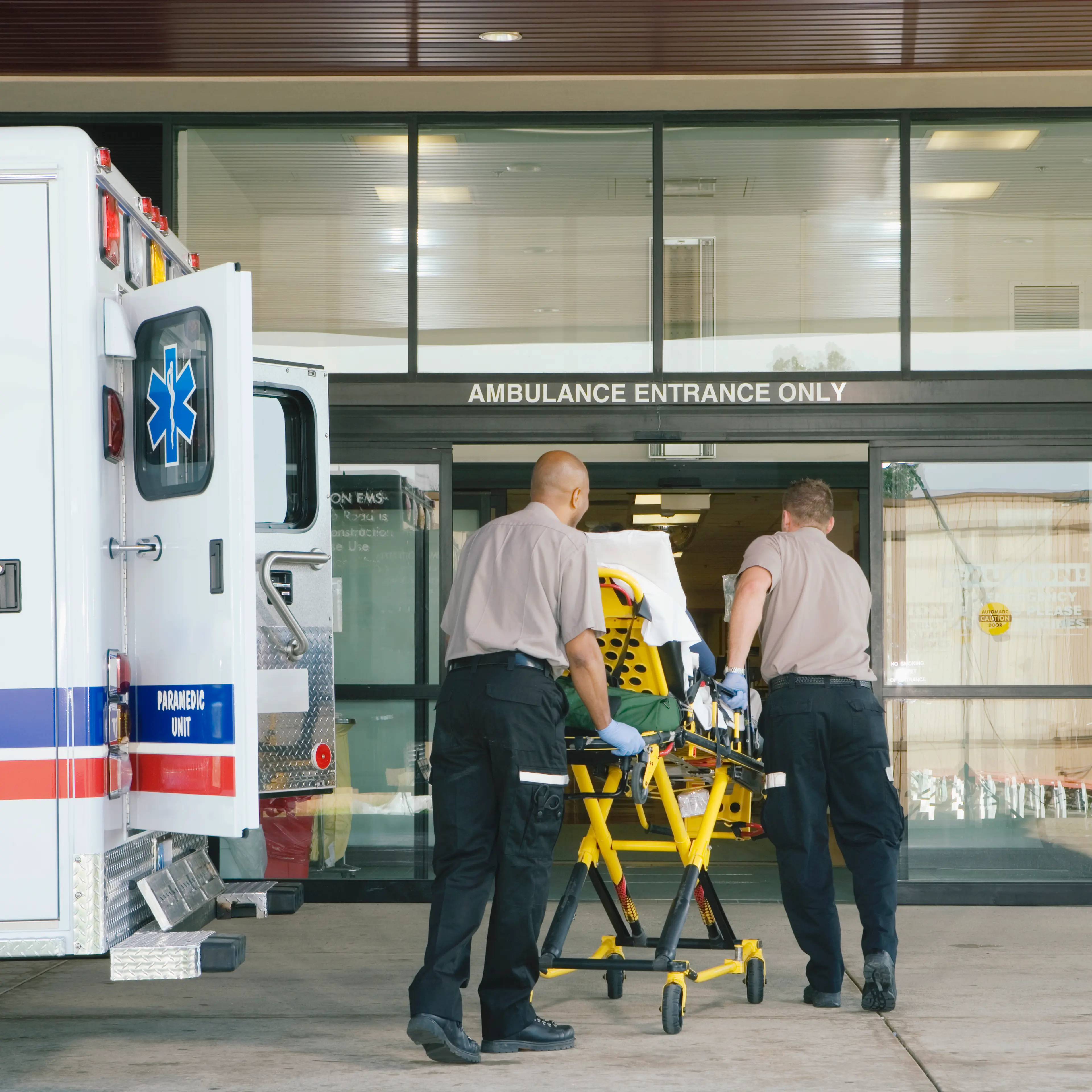 Paramedics taking patient on stretcher from ambulance to hospital
