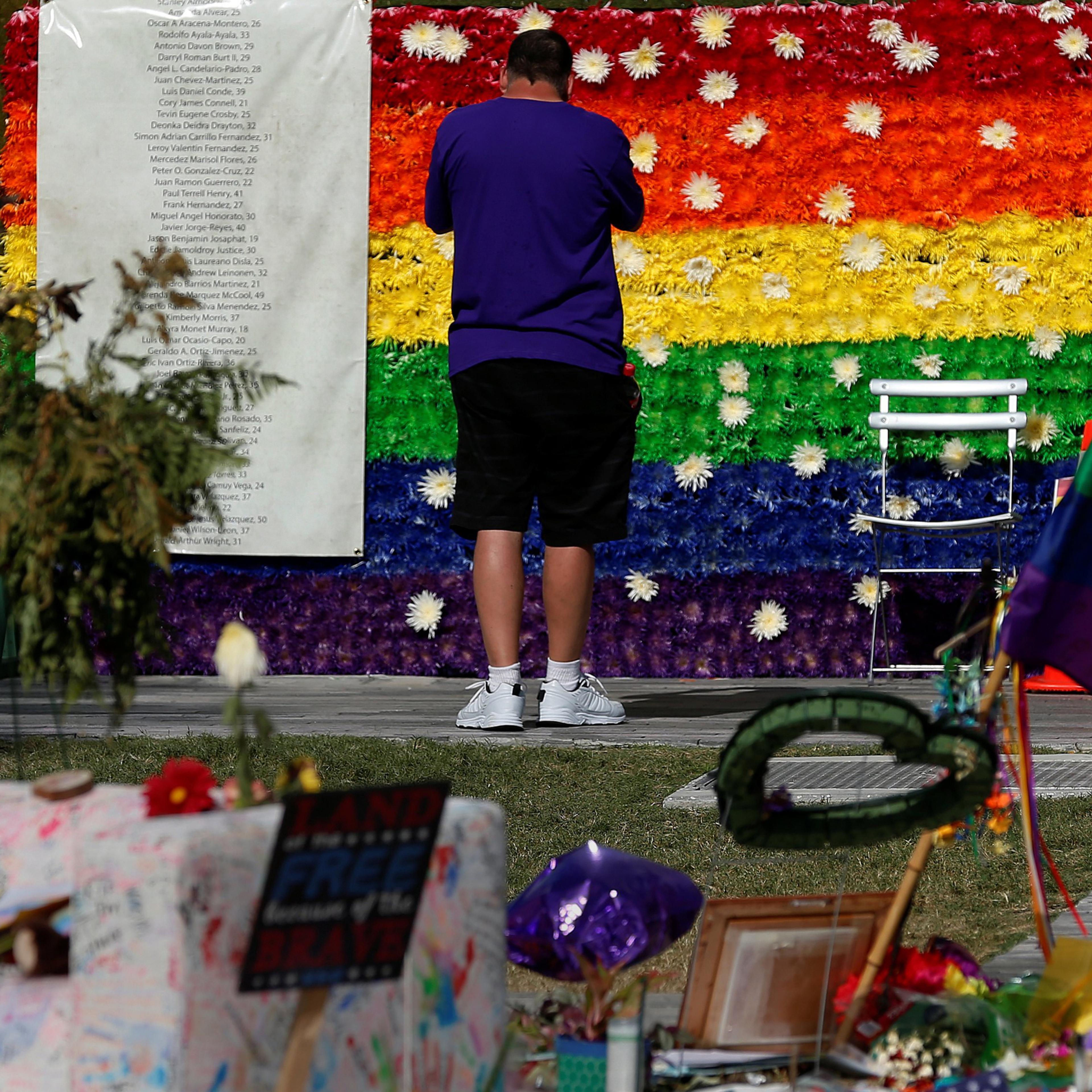 A man pays respect at a rainbow flower wall as part of the makeshift memorial for the Pulse nightclub mass shooting victims last week in Orlando, on June 21, 2016.