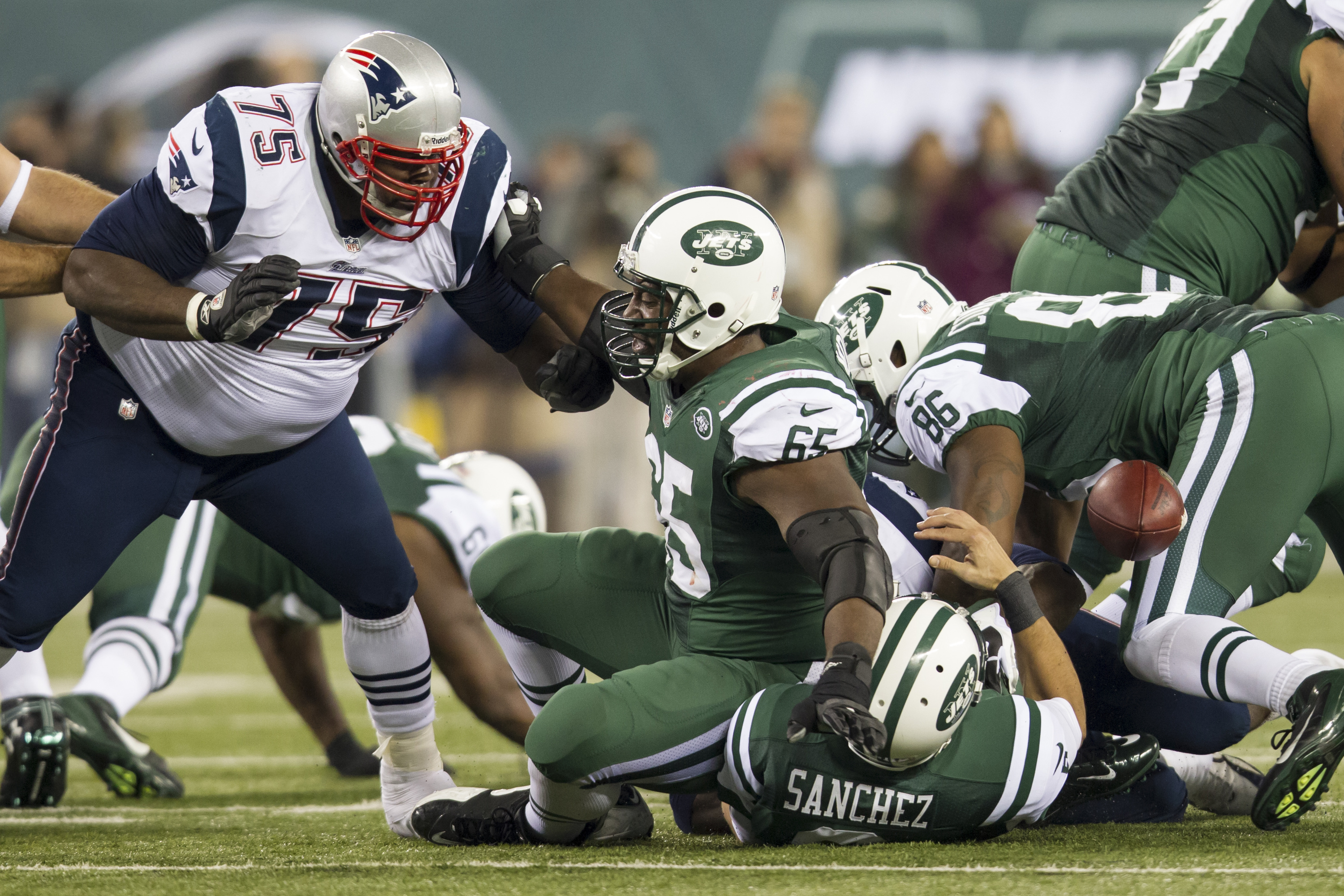 Patriots defensive tackle Vince Wilfork (75) pushes back New York Jets guard Brandon Moore (65) into quarterback Mark Sanchez (6) causing Sanchez to fumble the ball during the NFL Thanksgiving Day game between the New England Patriots and the New York Je