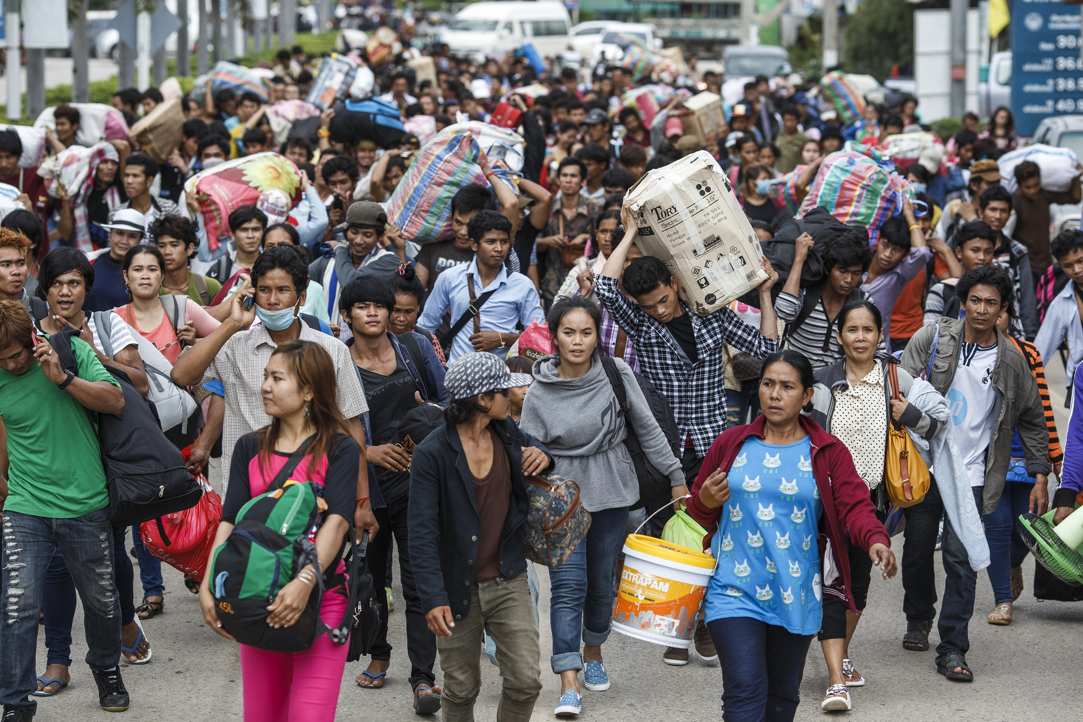 Cambodian migrant workers carry belongings as they walk to cross border at Aranyaprathet in Sa Kaew
