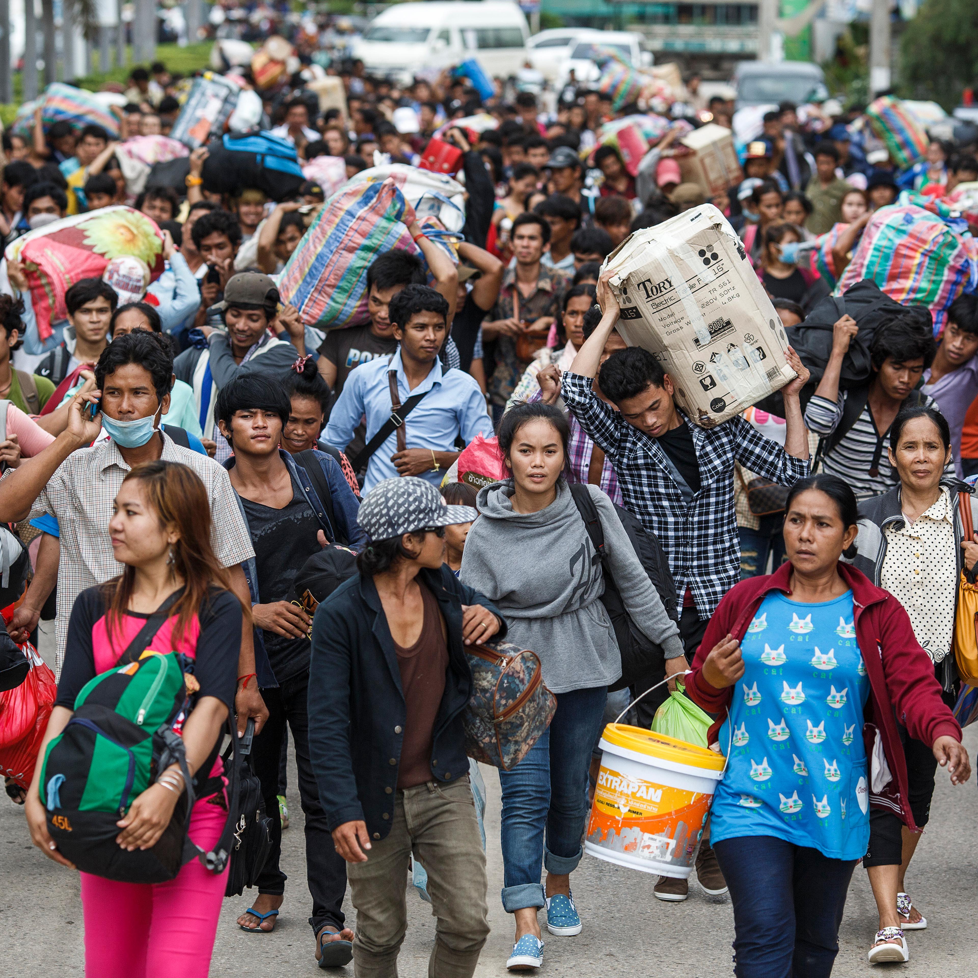 Cambodian migrant workers carry belongings as they walk to cross border at Aranyaprathet in Sa Kaew
