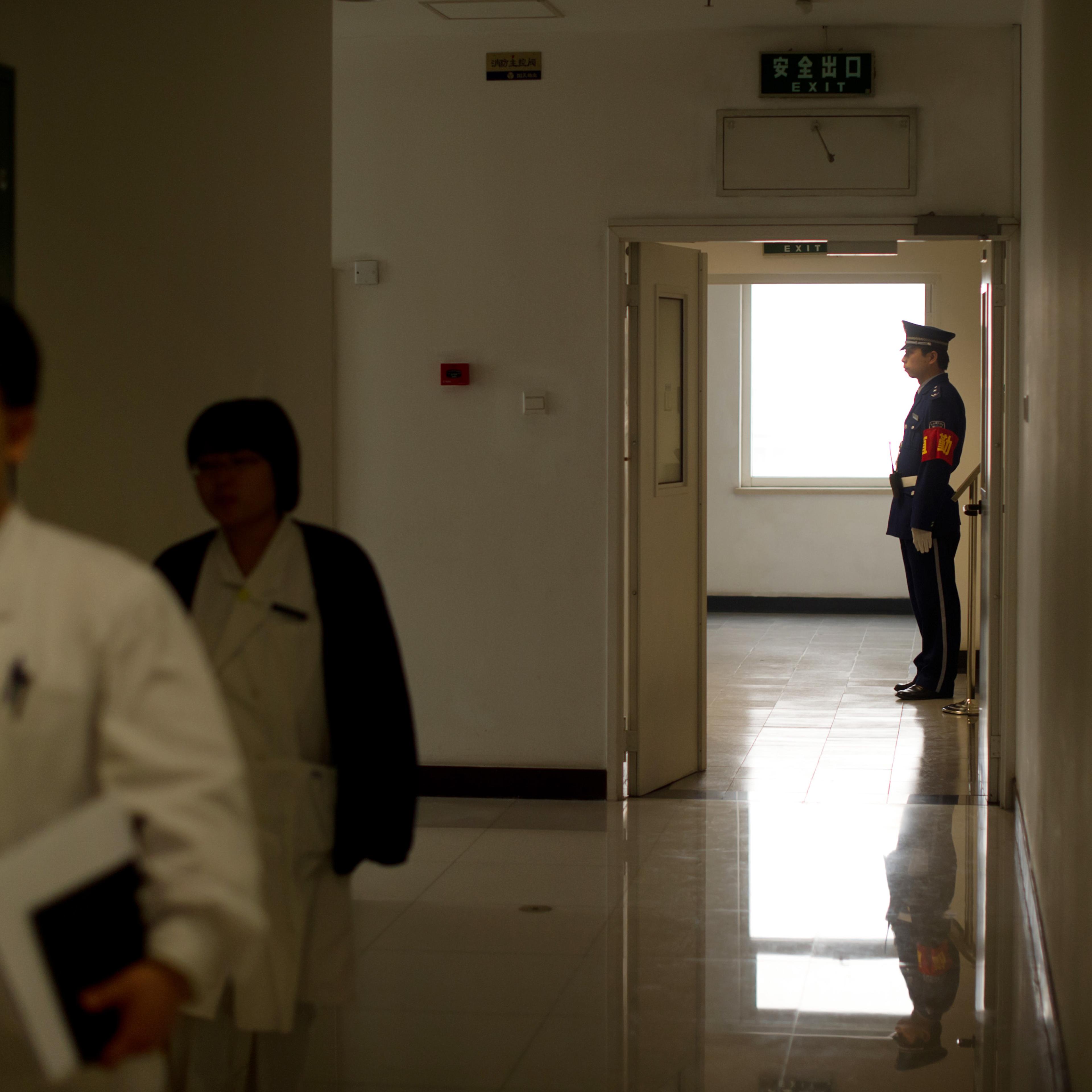 Hospital staff walk past a security guar