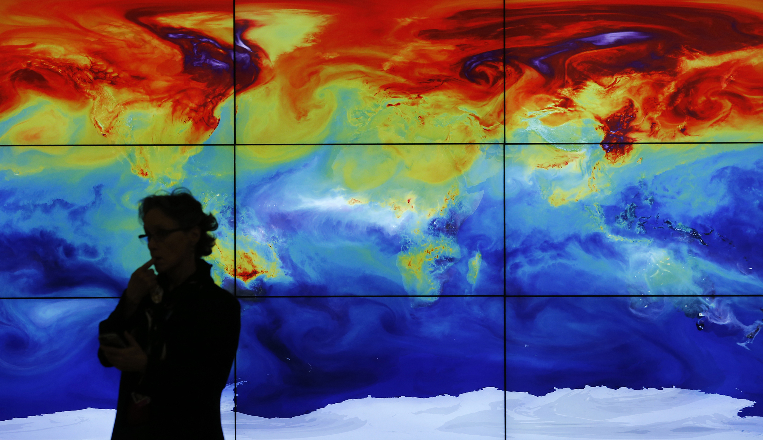 A participant is pictured in front of a screen projecting a world map during the World Climate Change Conference 2015 at Le Bourget, near Paris, Dec. 8, 2015.