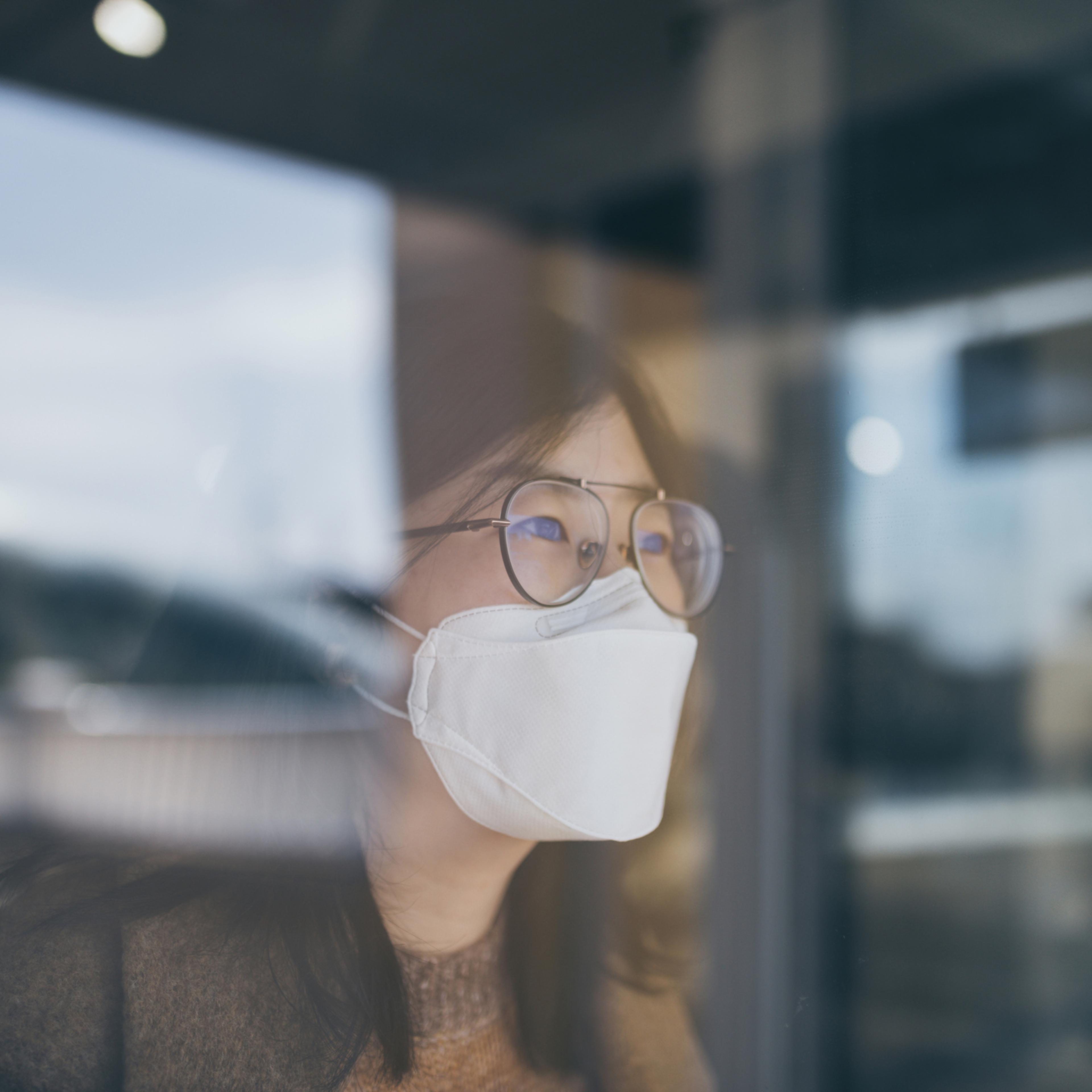 Woman looking through window with mask