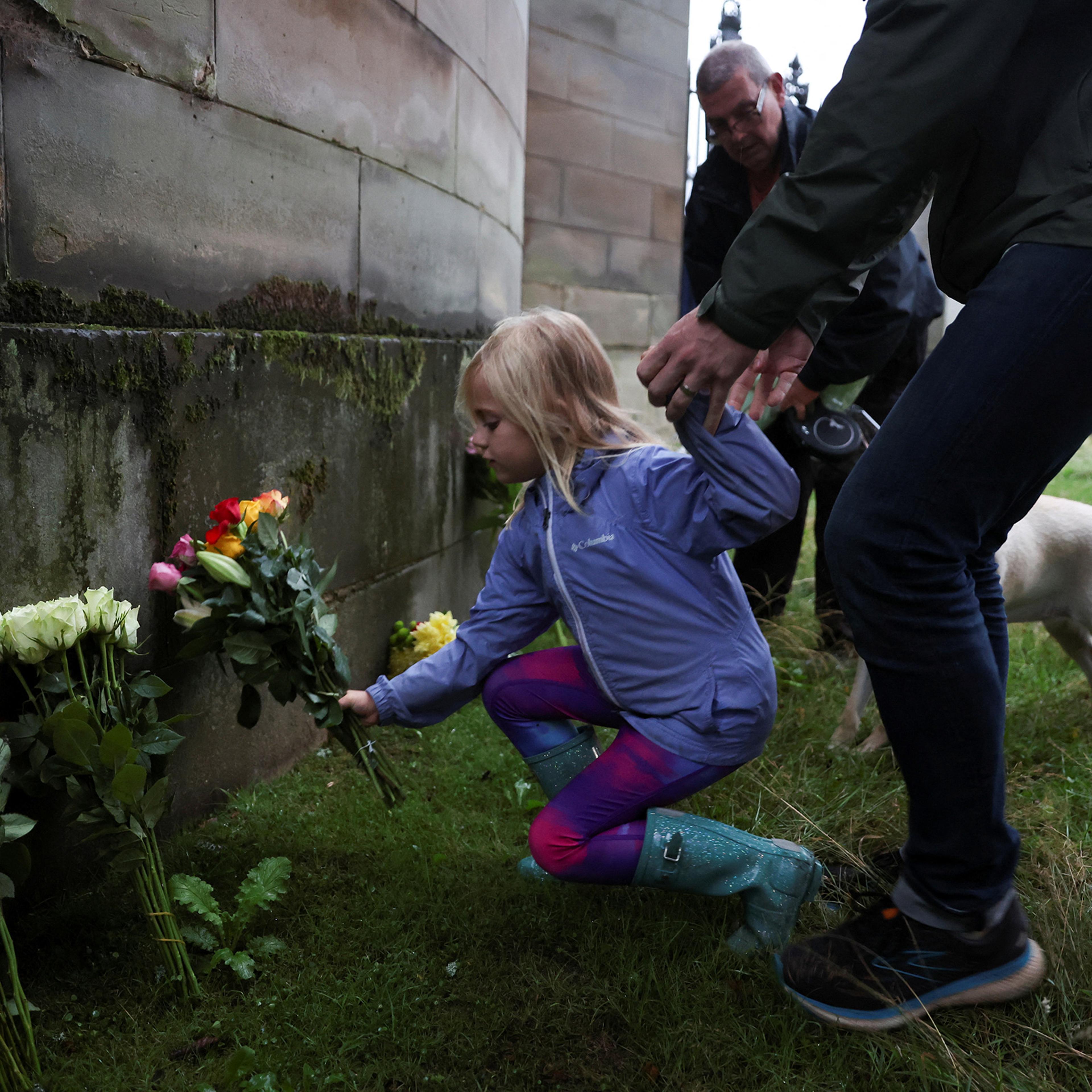 A child places flowers outside the Palace of Holyrood, Edinburgh, Scotland on Sept. 8 after the announcement that Queen Elizabeth, Britain's longest-reigning monarch and the nation's figurehead for seven decades, died aged 96.