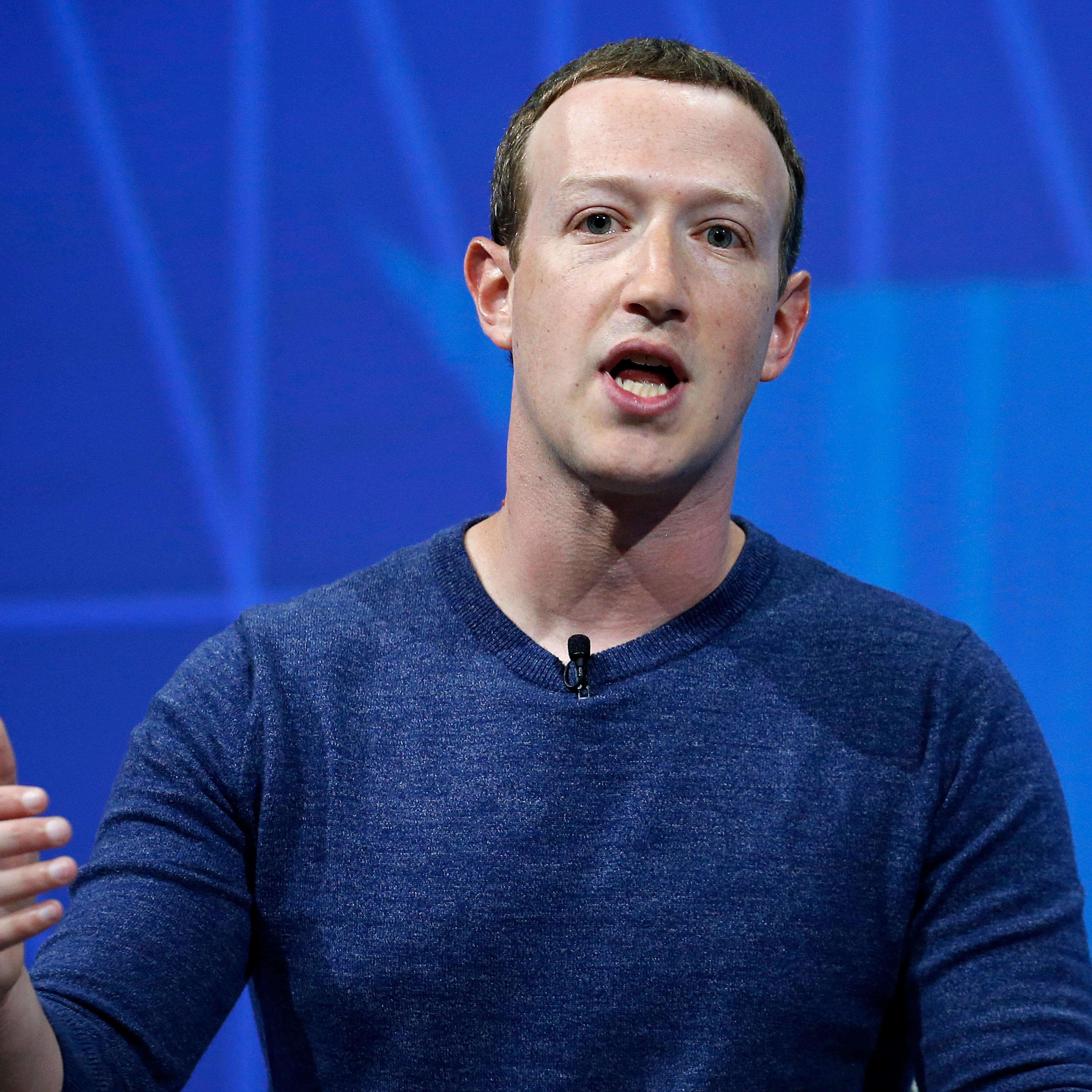 Mark Zuckerberg speaks at a conference in front of a blue screen