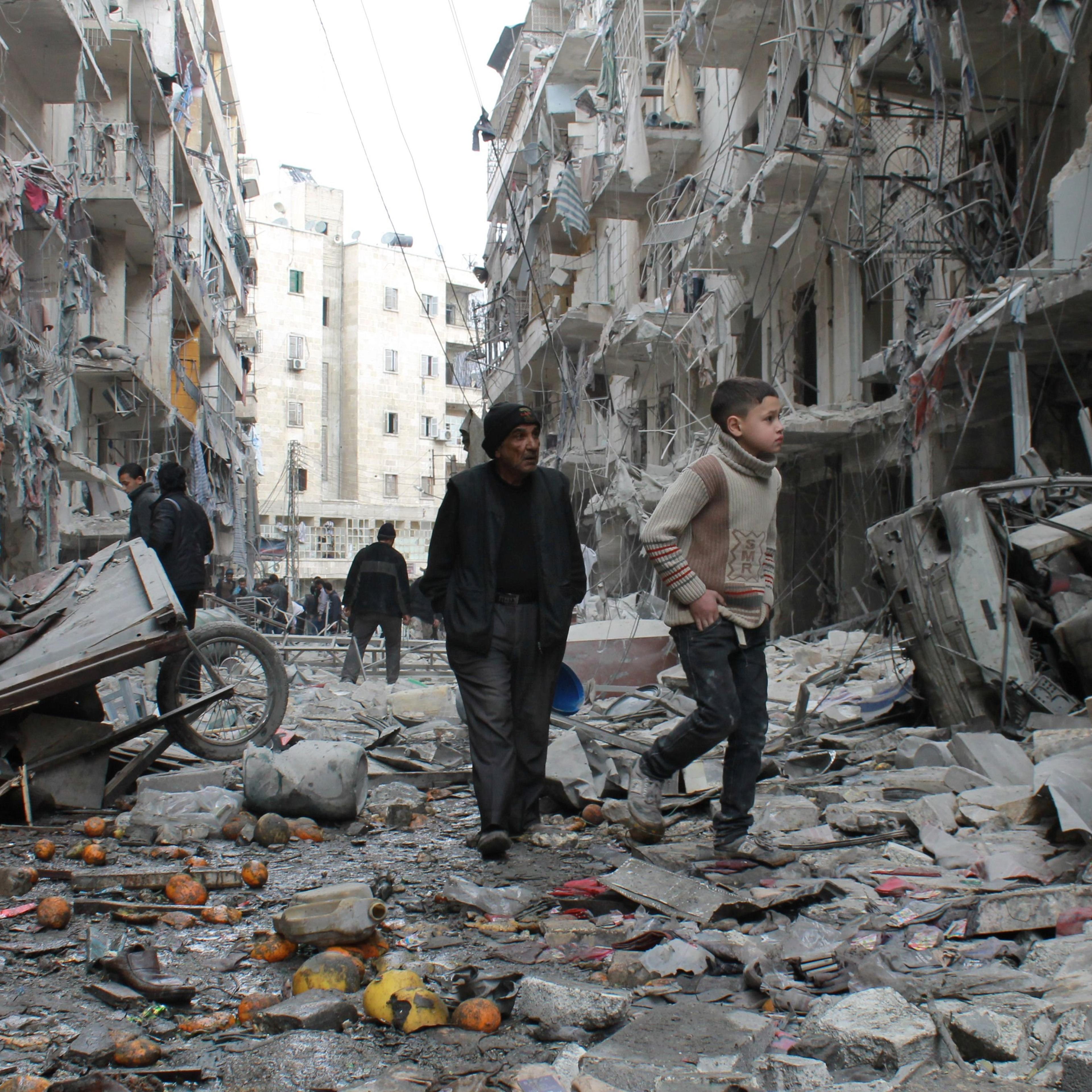 An elderly Syrian man and a child walk amidst debris in a residential block reportedly hit by an explosives-filled barrel dropped by a government forces helicopter on March 18, 2014 in Aleppo.