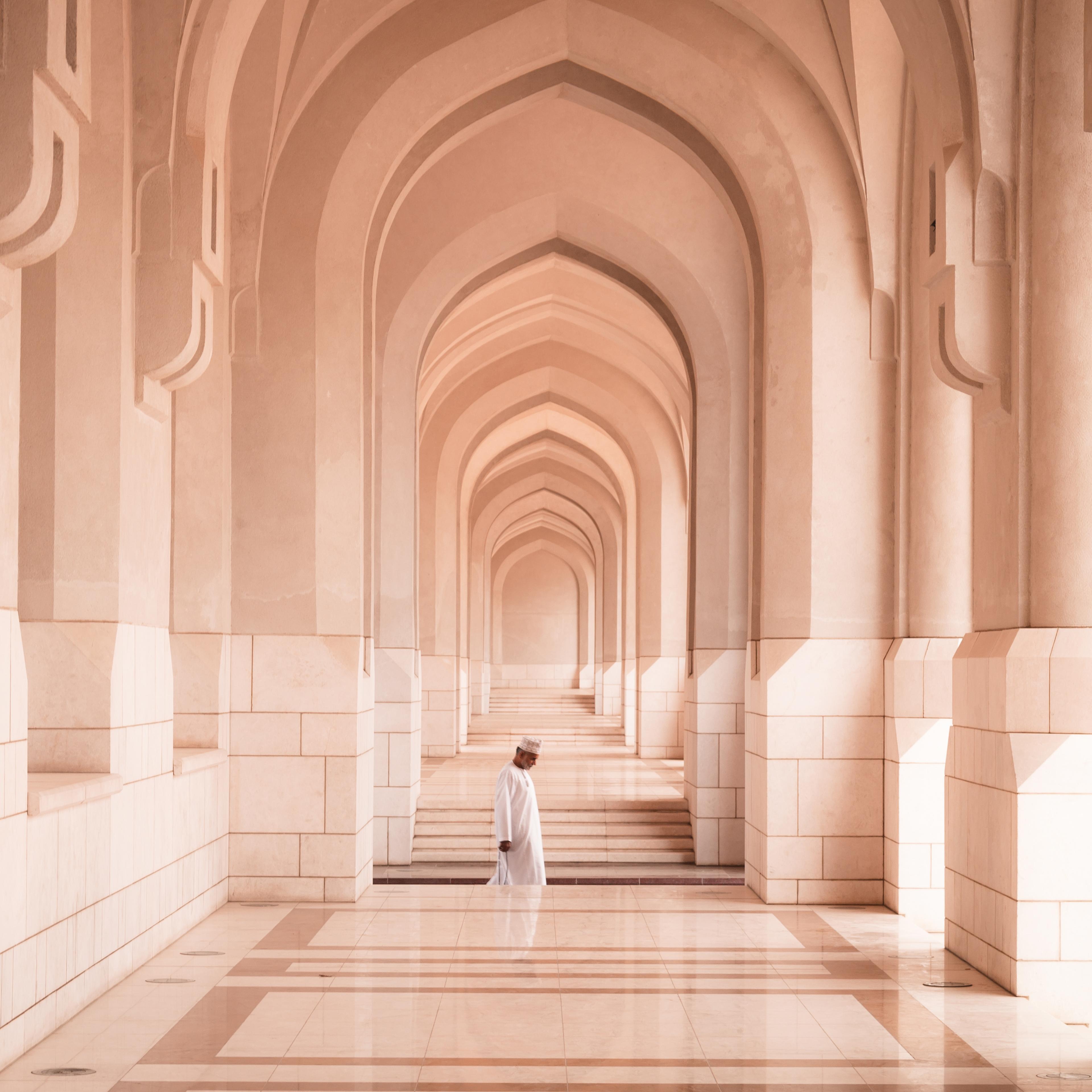 Man passing through arches of colonnade, Oman