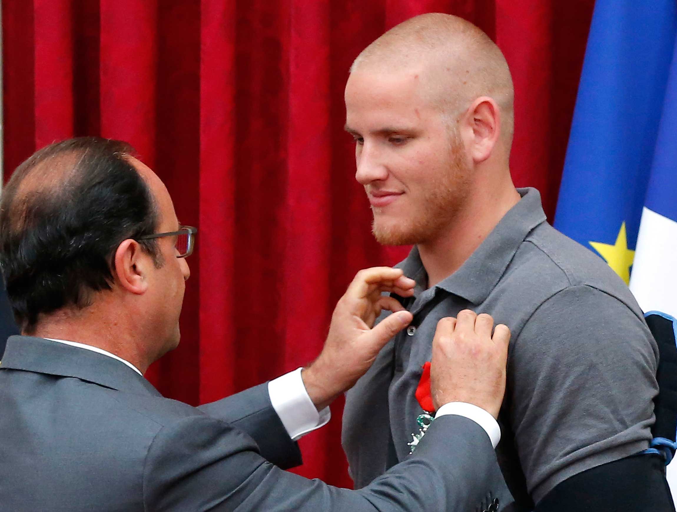 French President Francois Hollande awards US Airman First Class Spencer Stone with the Legion d'Honneur medal as US National Guardsman Alek Skarlatos applauds during a ceremony at the Elysee Palace in Paris