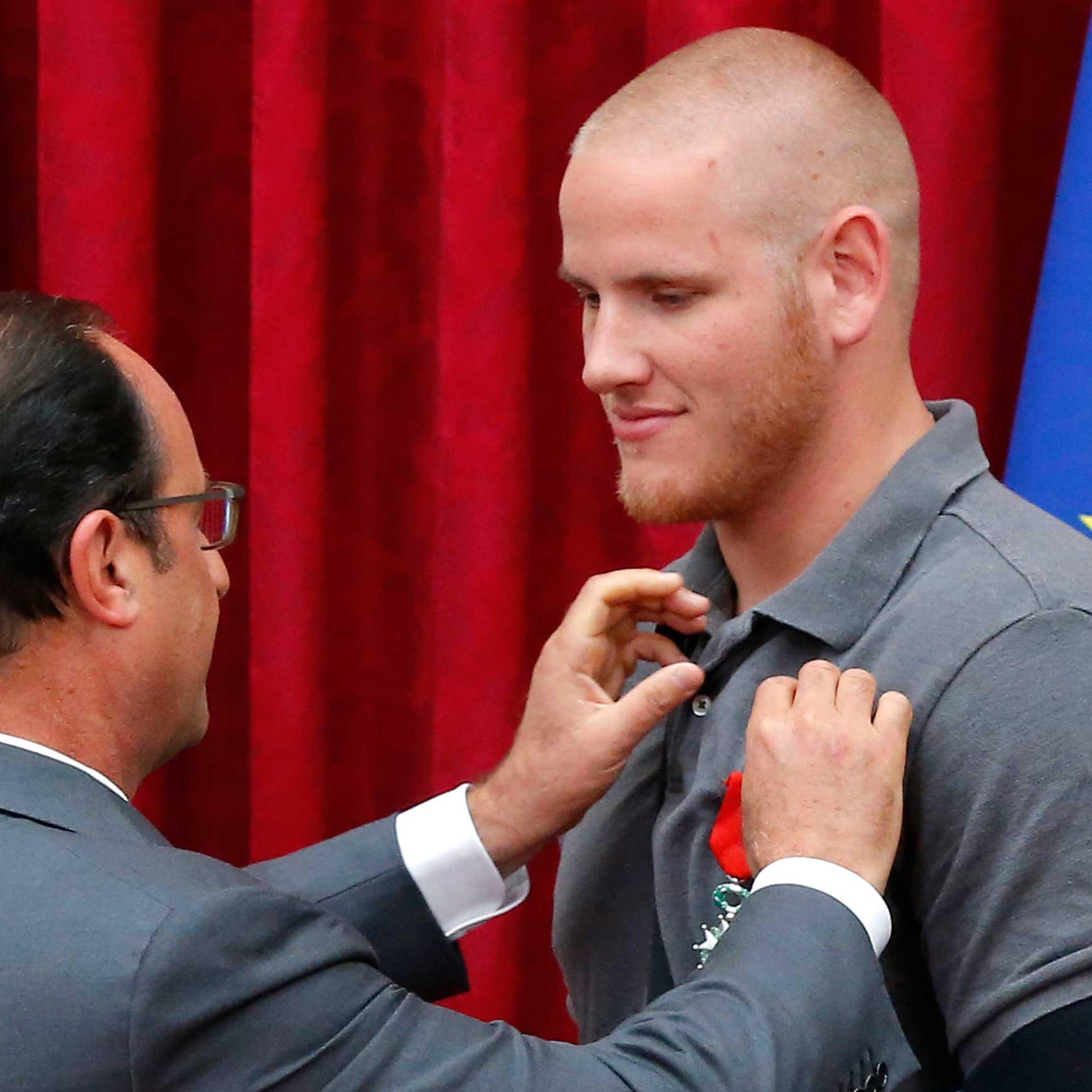 French President Francois Hollande awards US Airman First Class Spencer Stone with the Legion d'Honneur medal as US National Guardsman Alek Skarlatos applauds during a ceremony at the Elysee Palace in Paris