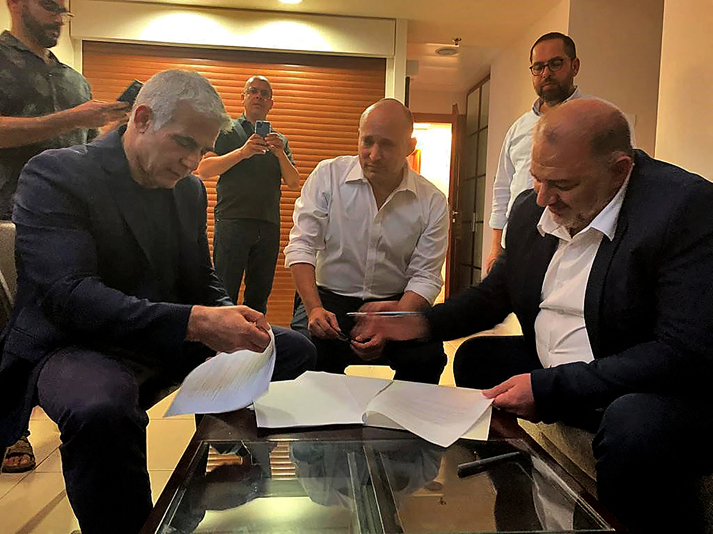 A handout picture provided by the United Arab List on June 2, 2021, shows Mansour Abbas, right, signing a coalition agreement with Israel's opposition leader Yair Lapid, left, and right-wing nationalist Naftali Bennett in Ramat Gan near the coastal city 