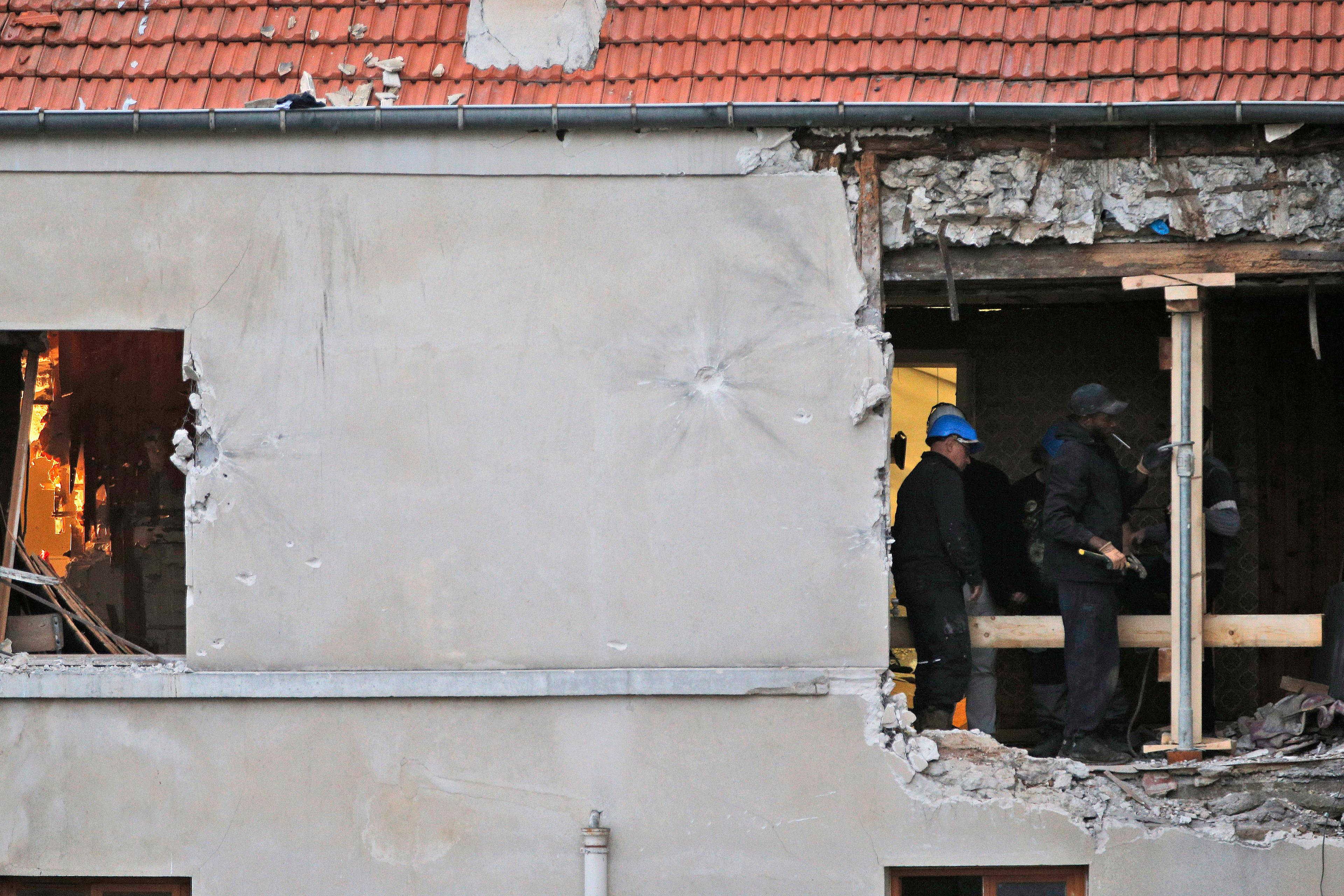 People work inside the damaged building of Wednesday's raid on an apartment in the Paris suburb of Saint-Denis on Nov.19, 2015.